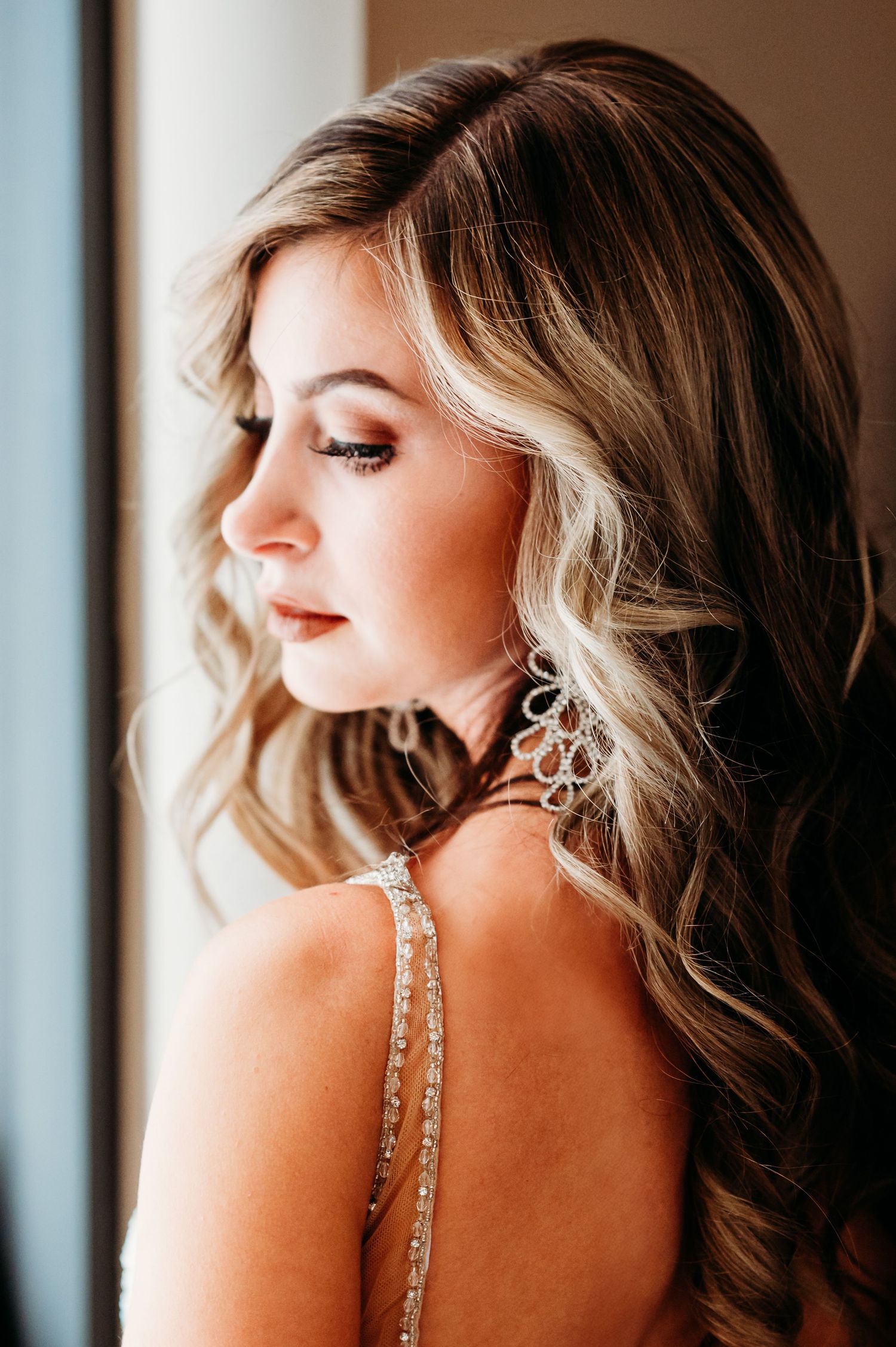 Side profile shots showcase sparkly chandelier earrings with elegant wavy hair.