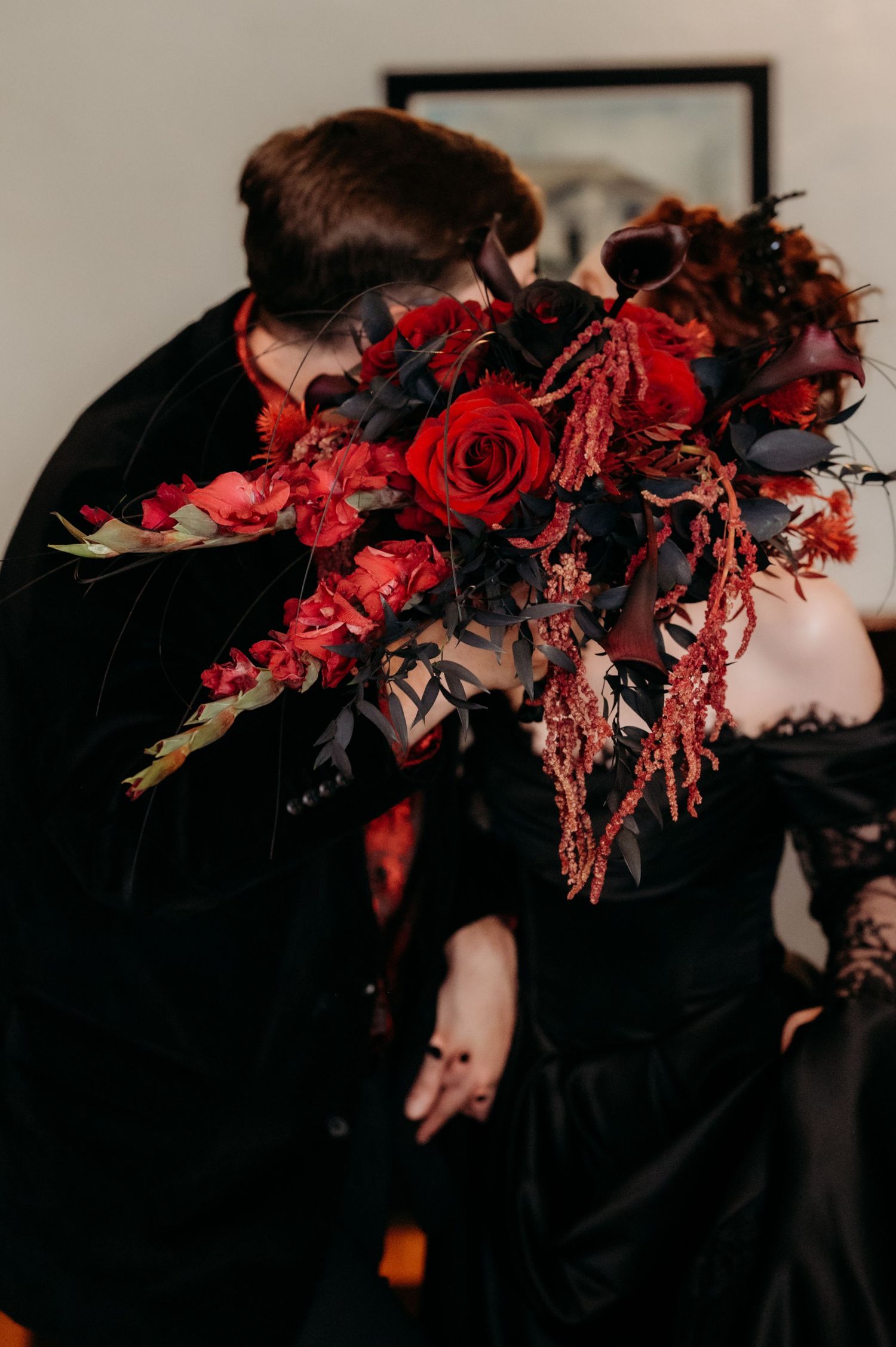 Dramatic black and red floral crown with roses and dried flowers displayed in a dark moody setting.