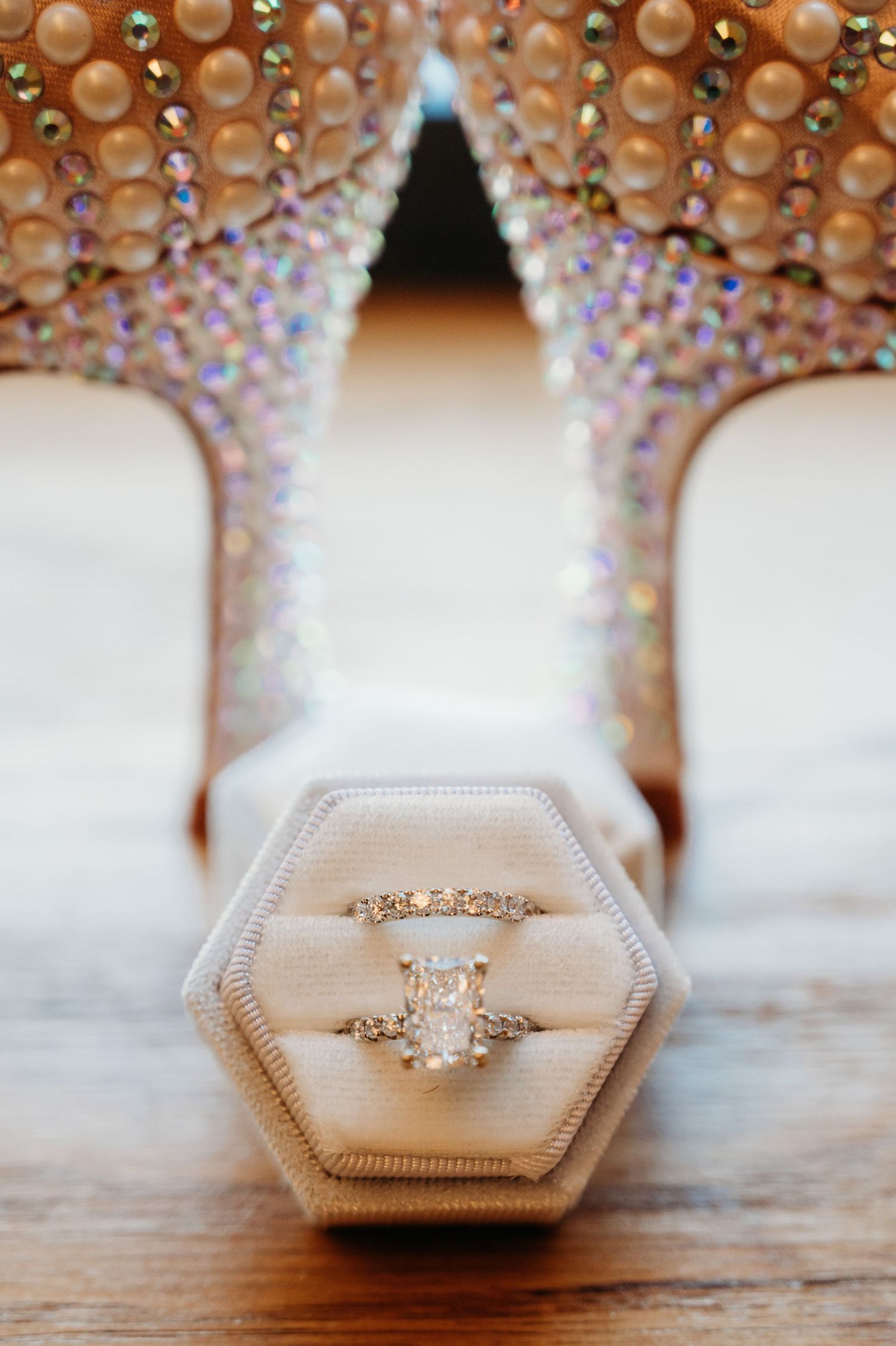 Diamond engagement ring in hexagonal box under crystal chandelier lighting.