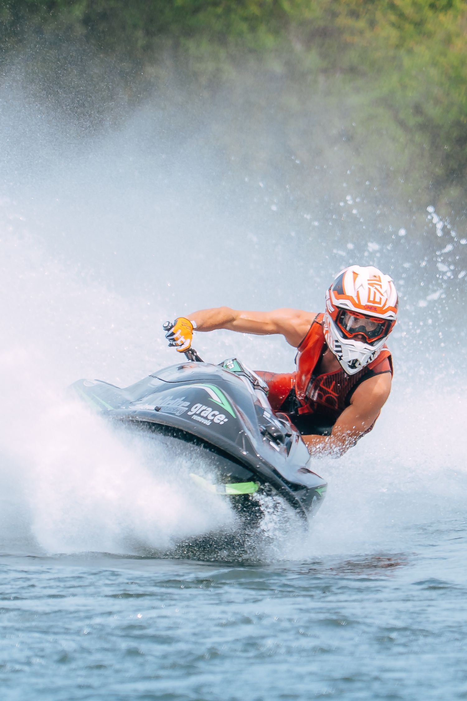 Jet ski rider looking ahead while he performs a dramatic turn creating splash on blue water during competition in Christchurch.