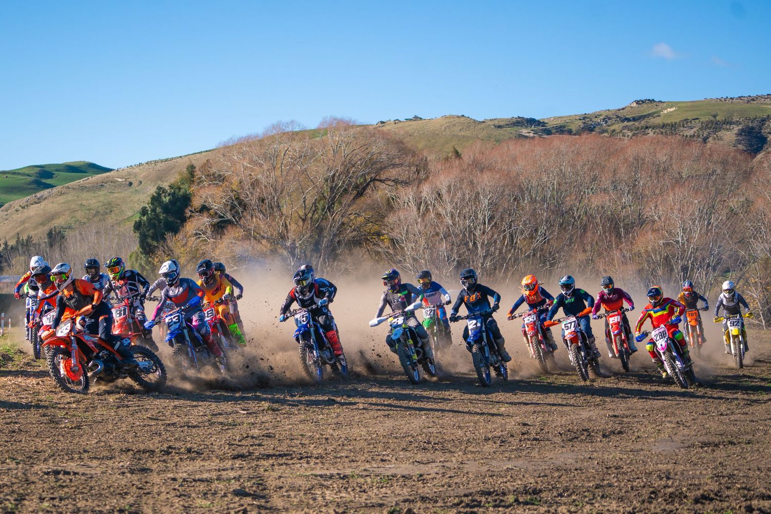 Long line of dirt bike riders racing across a dusty hillside track at the Michael Godfrey Memorial Race in North Canterbury 2025.