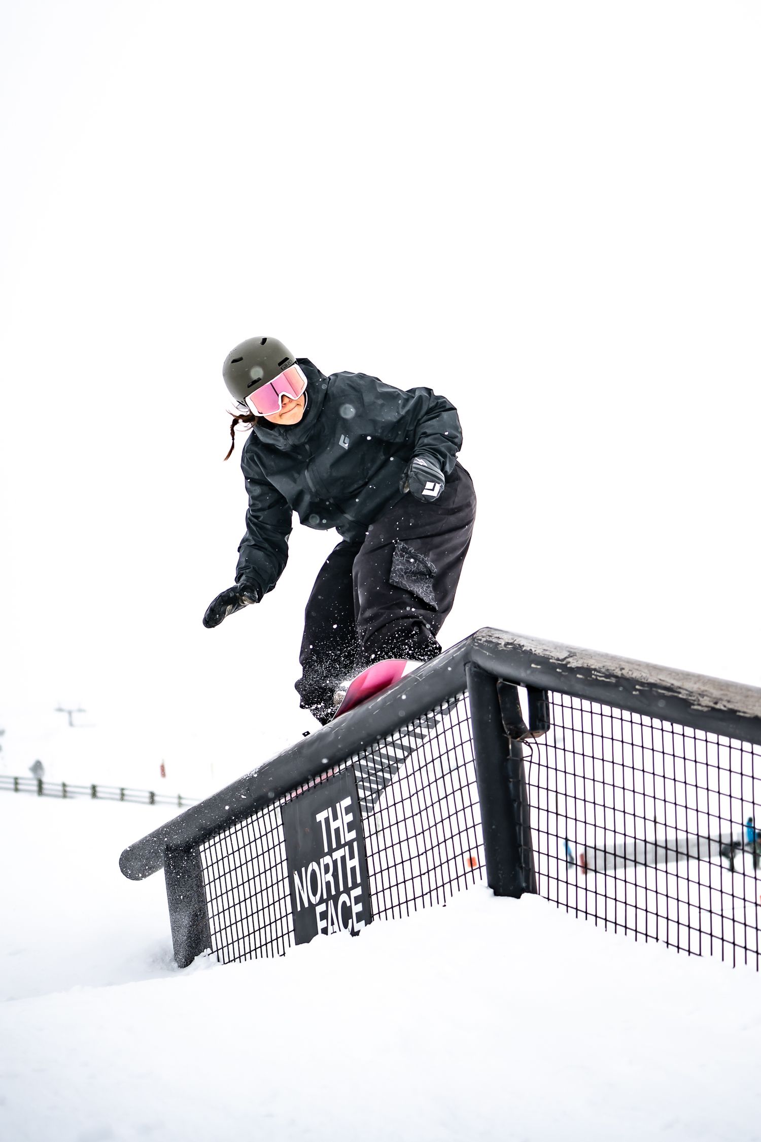 Female snowboarder performs boardslide trick on metal rail in snowy winter terrain during action sports sequence at Cardrona Alpine Report.