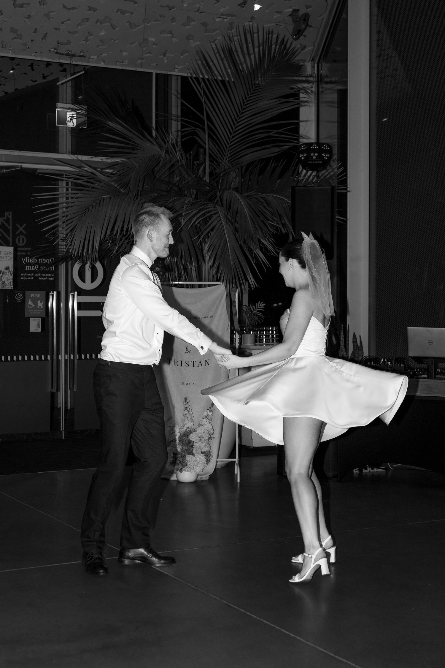 Black and white photo of a couple dancing elegantly, woman in white dress, man in white shirt and black trousers.
