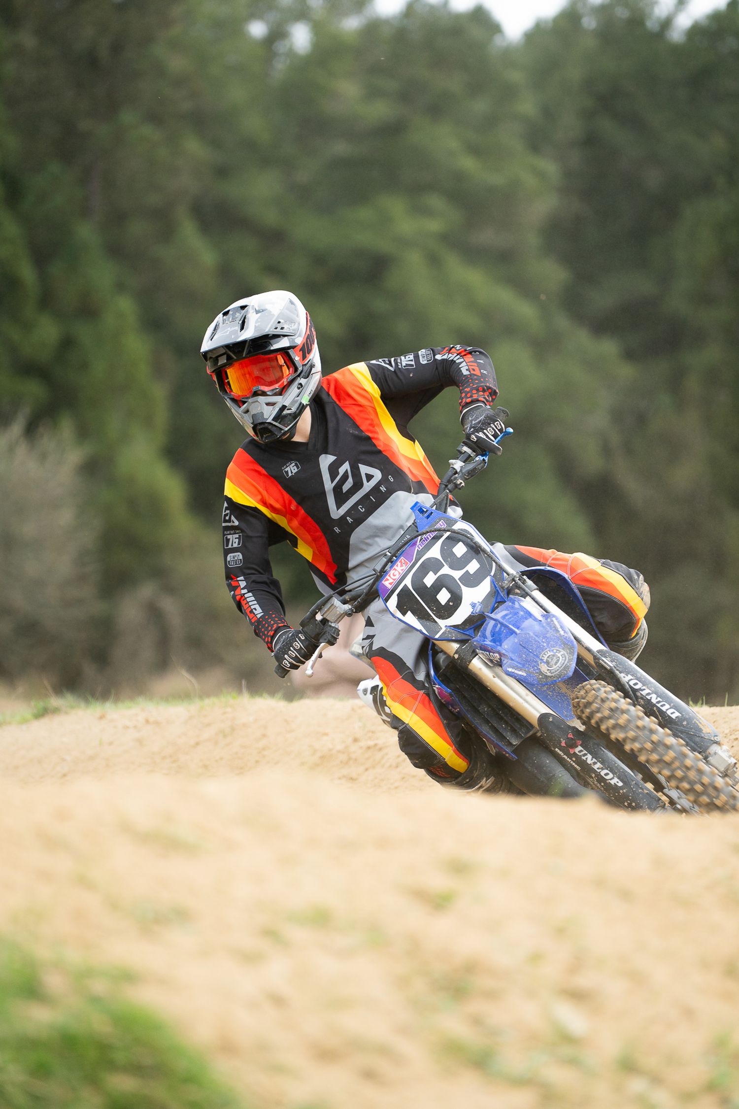 Dirt bikes lean into sharp turn on motocross track during intense race competition on the West Coast, South Island of New Zealand.