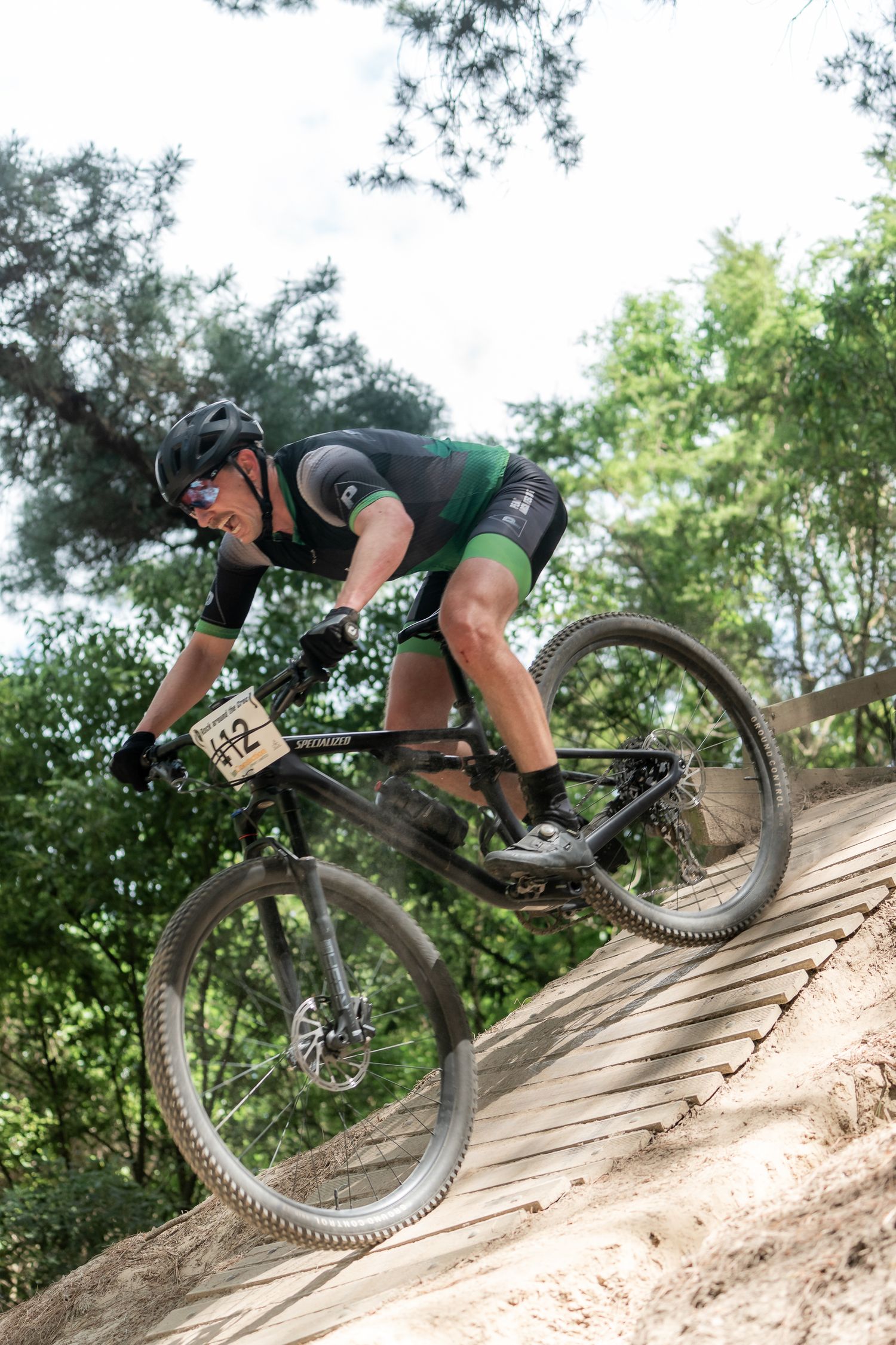 Mountain biker navigates a steep wooden ramp on a trail through green forest terrain at the Halswell Crocodile Park in Christchurch,