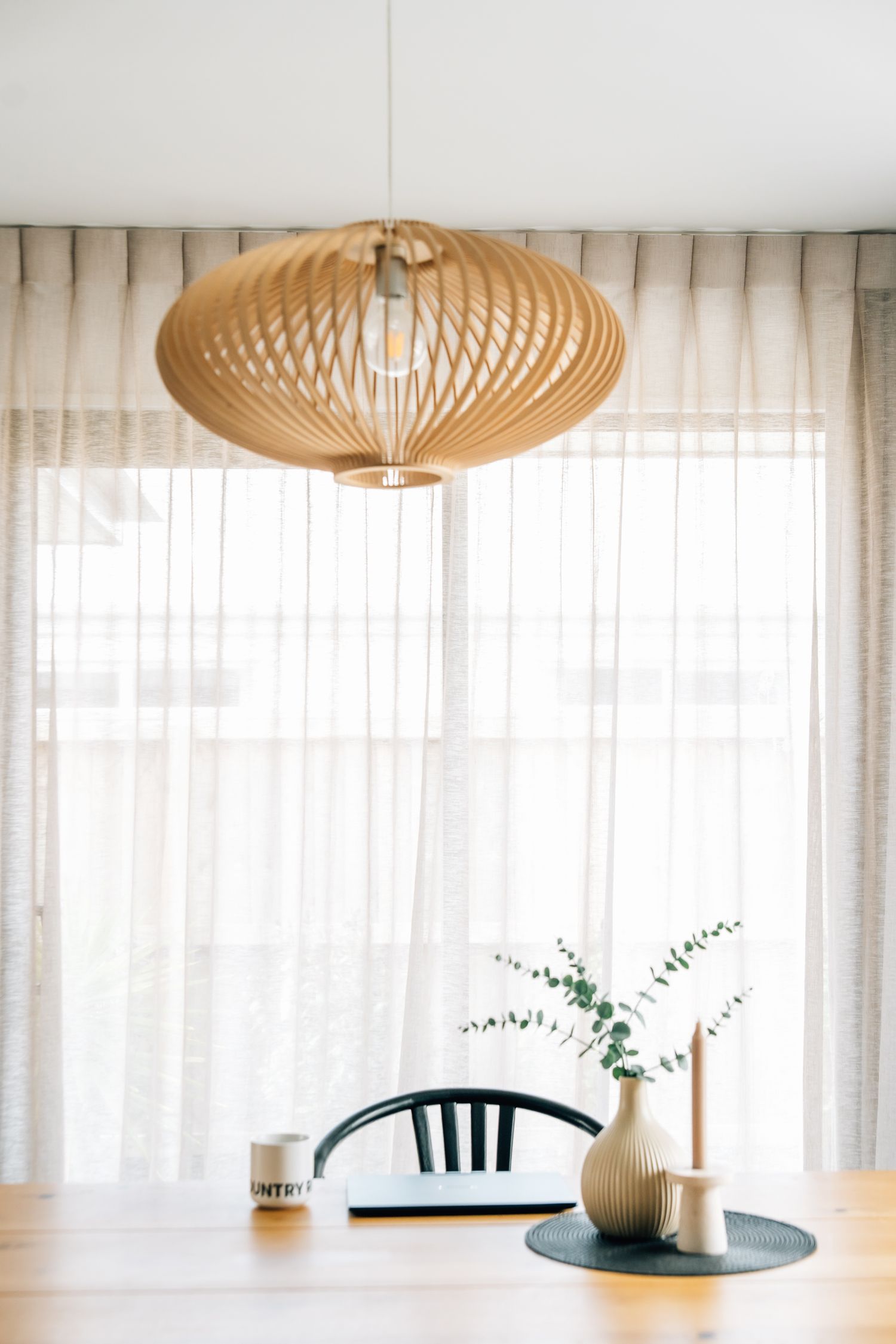 Modern pendant light fixtures with bamboo woven shades hang elegantly above a dining area for a branding photoshoot in Christchurch.