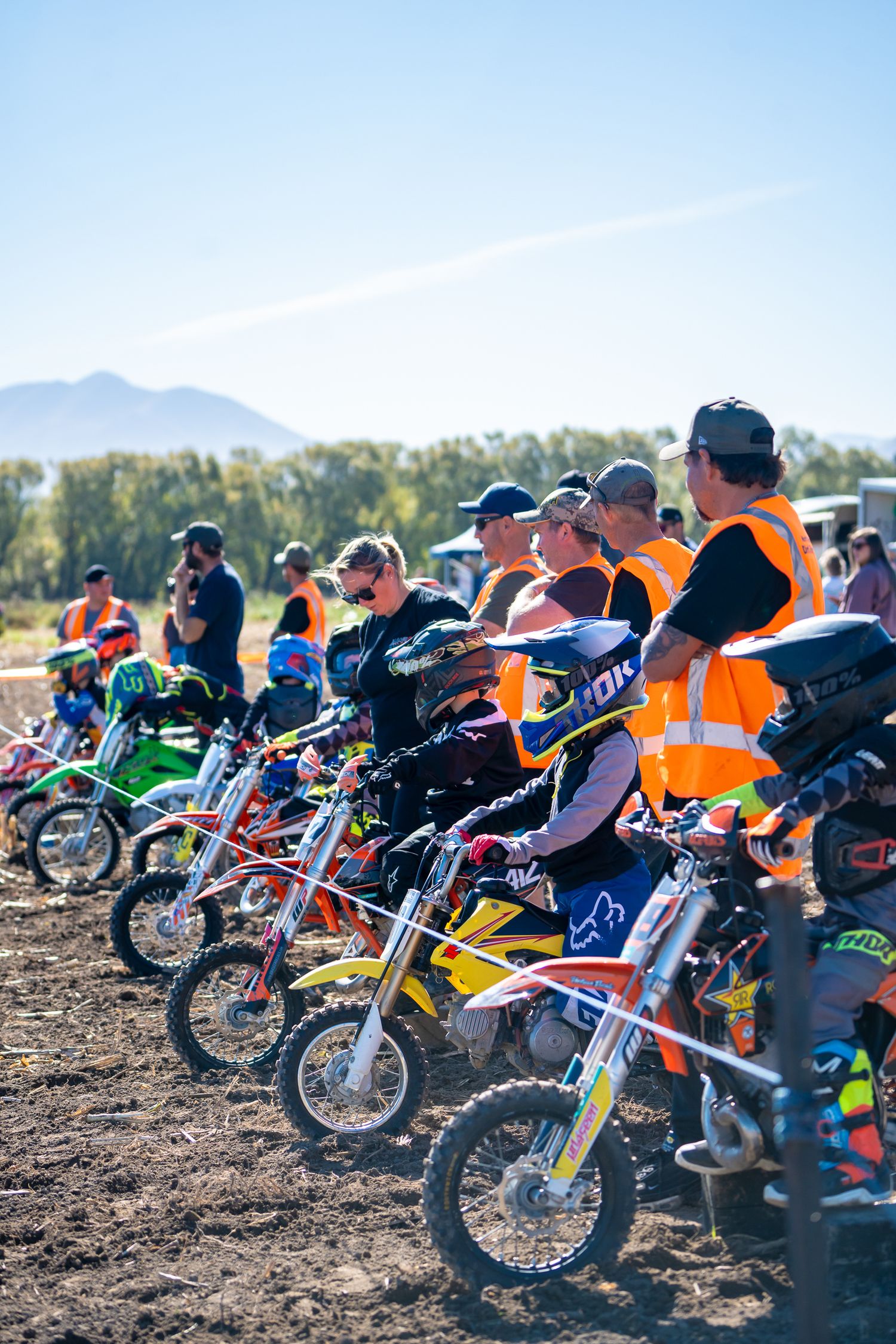 Row of colorful dirt bikes and riders waiting at the start of a motocross competition at a funday in North Canterbury.