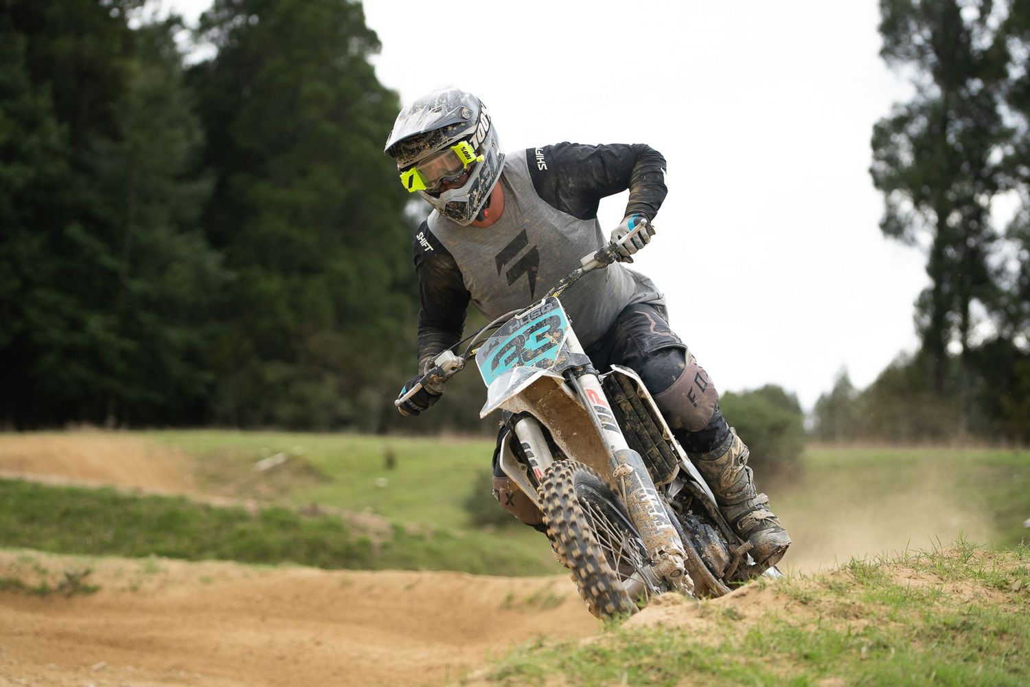 Motocross riders navigate dusty track corner during competitive race event in the South Island of New Zealand.