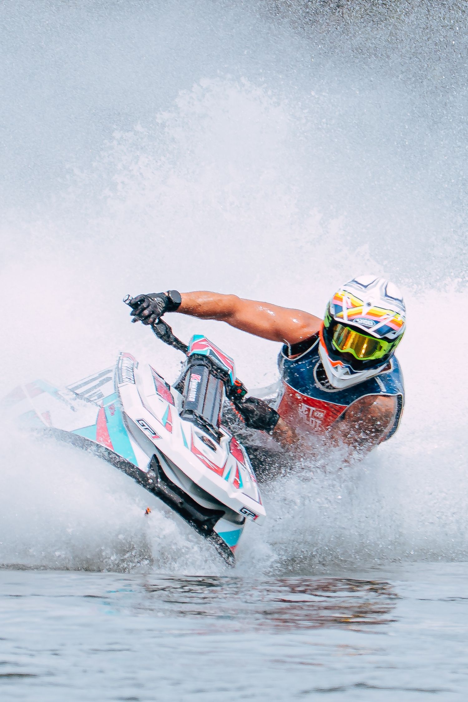 A jet ski rider performing a high-speed turn creating dramatic water spray on a blue lake in Christchurch.