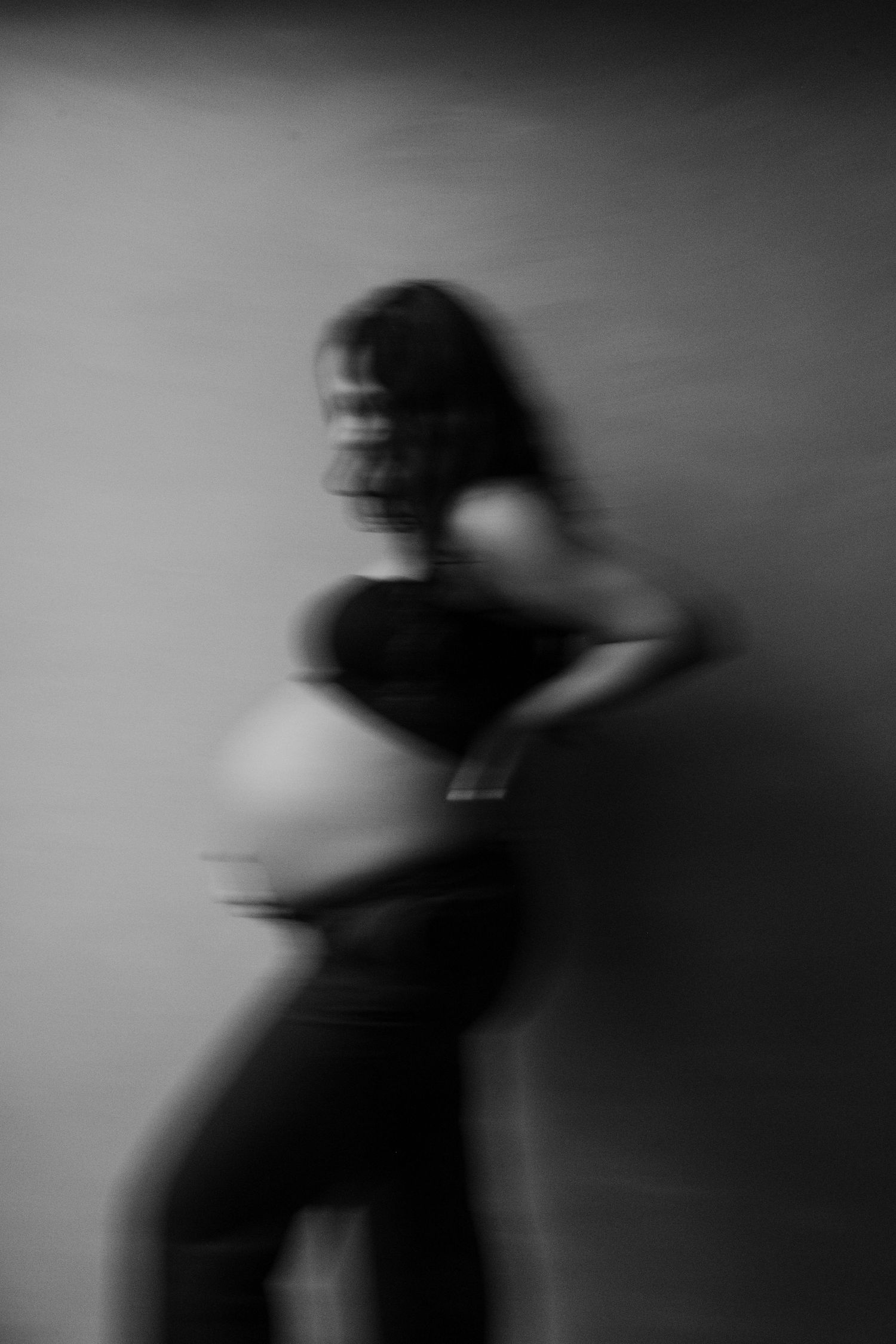 A series of blurred black and white motion photographs showing a dark silhouette figure moving against a light background.