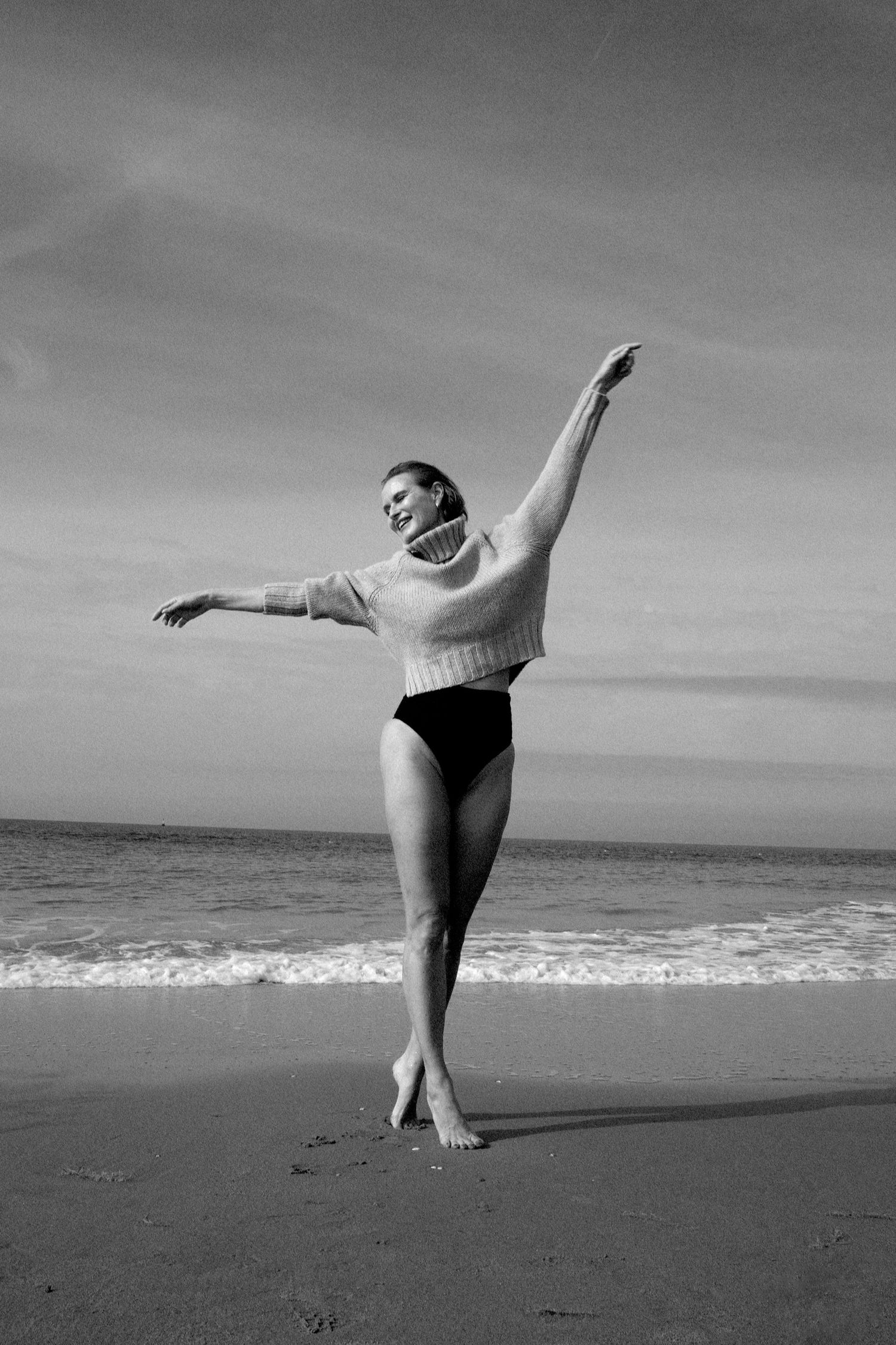 Black and white beach dance sequence showing expressive movements on sand.