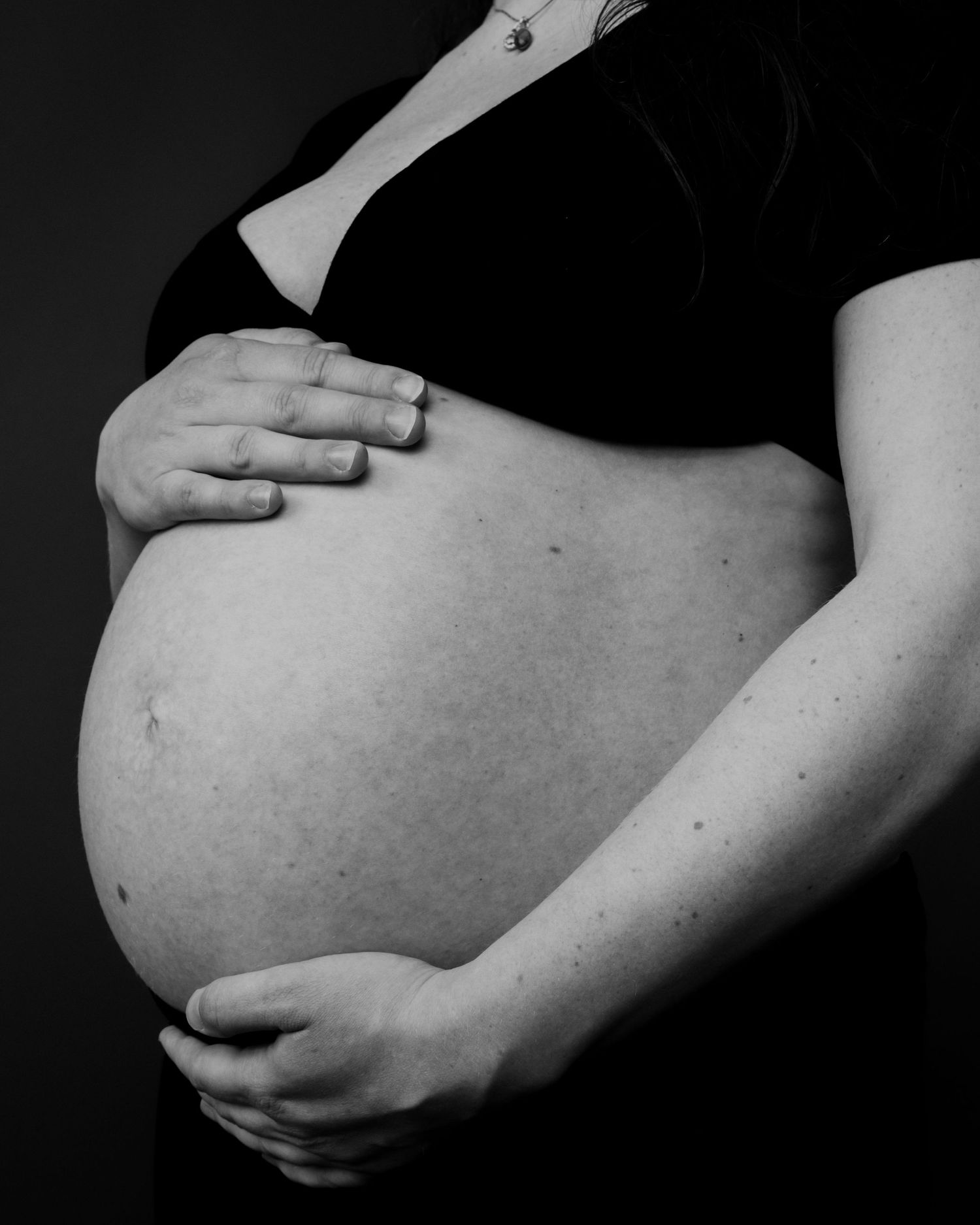 A series of black and white photographs showing a pregnant belly at different angles in artistic composition.