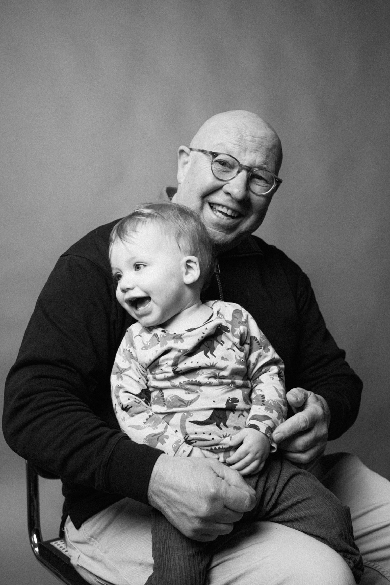 A black and white photo series shows tender moments between a baby and adult in matching glasses.