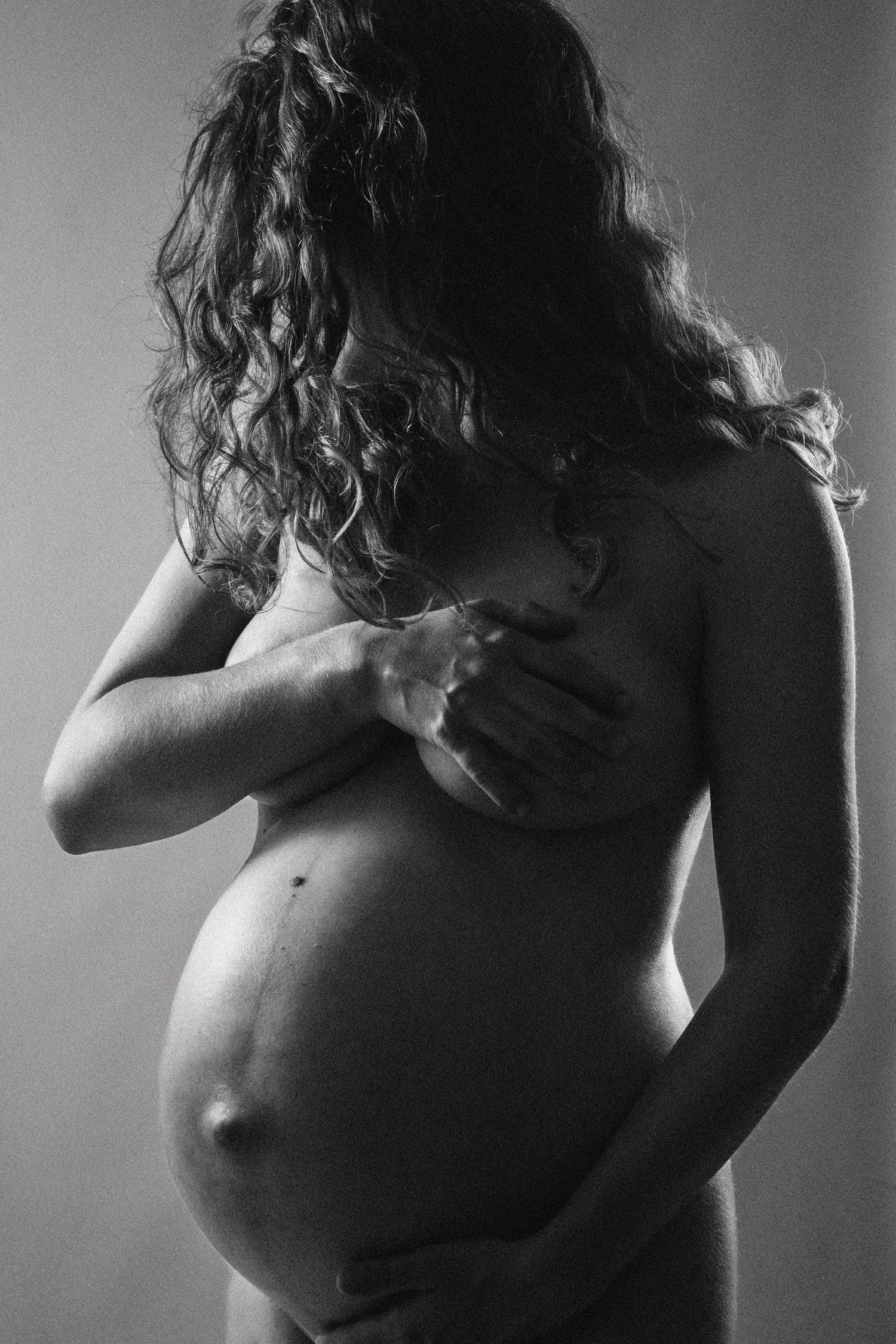 Artistic black and white nude figure study showing torso in dramatic lighting.