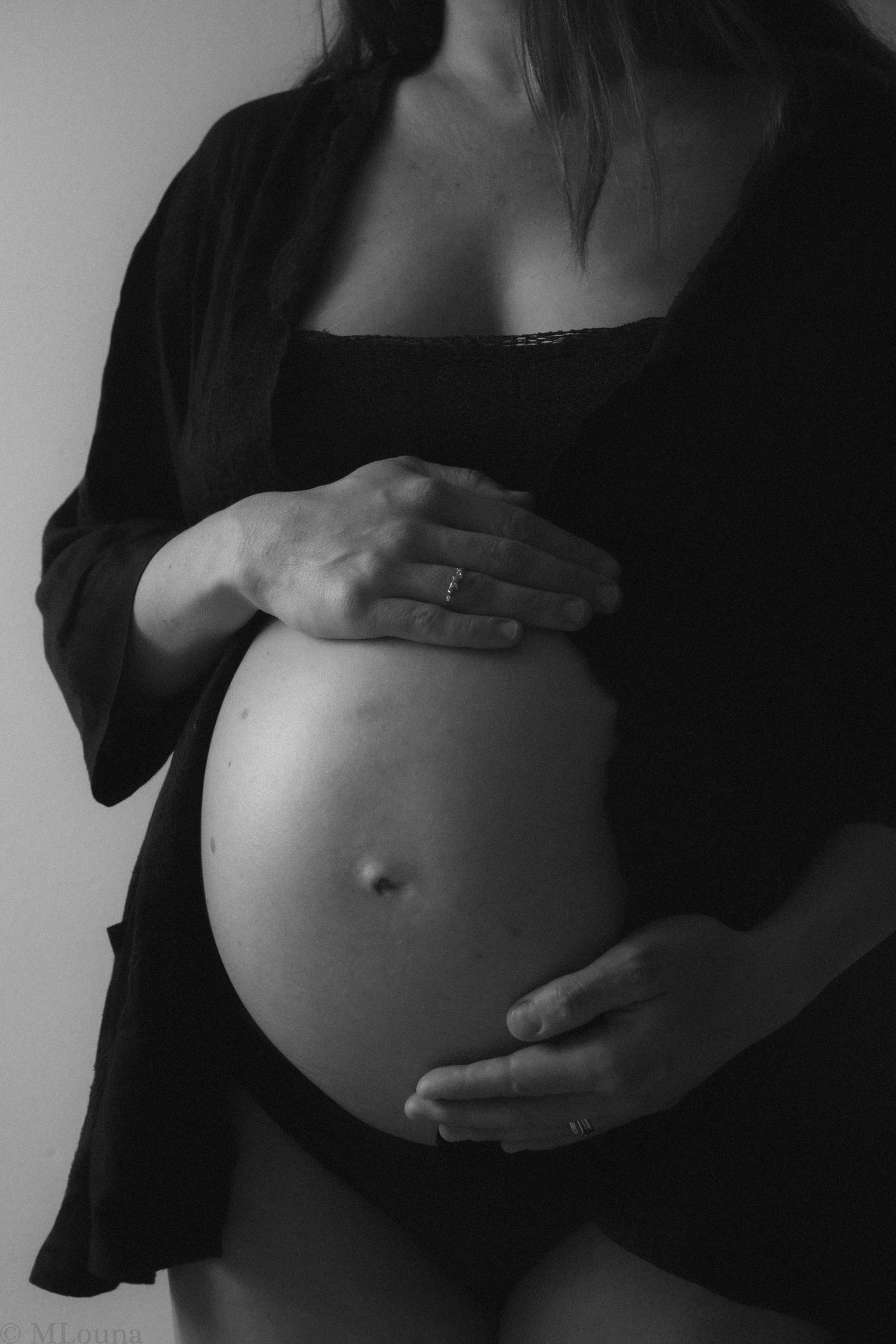 A black and white photo series showing the progression of a pregnant belly with hands cradling the growing bump.