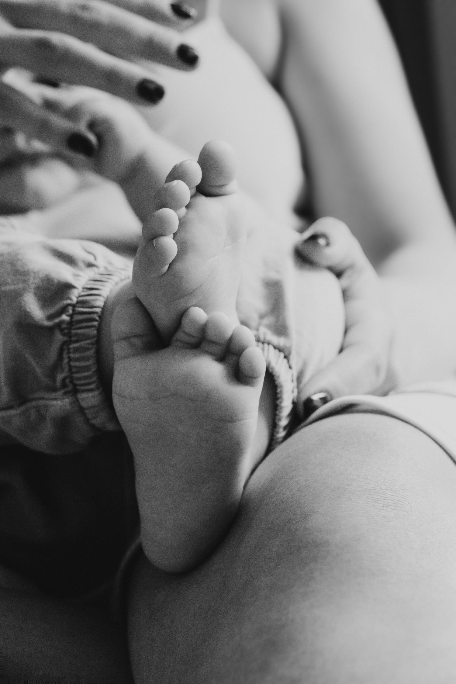 A series of black and white close-up photos showing gentle hands holding a baby's tiny feet in a tender moment.