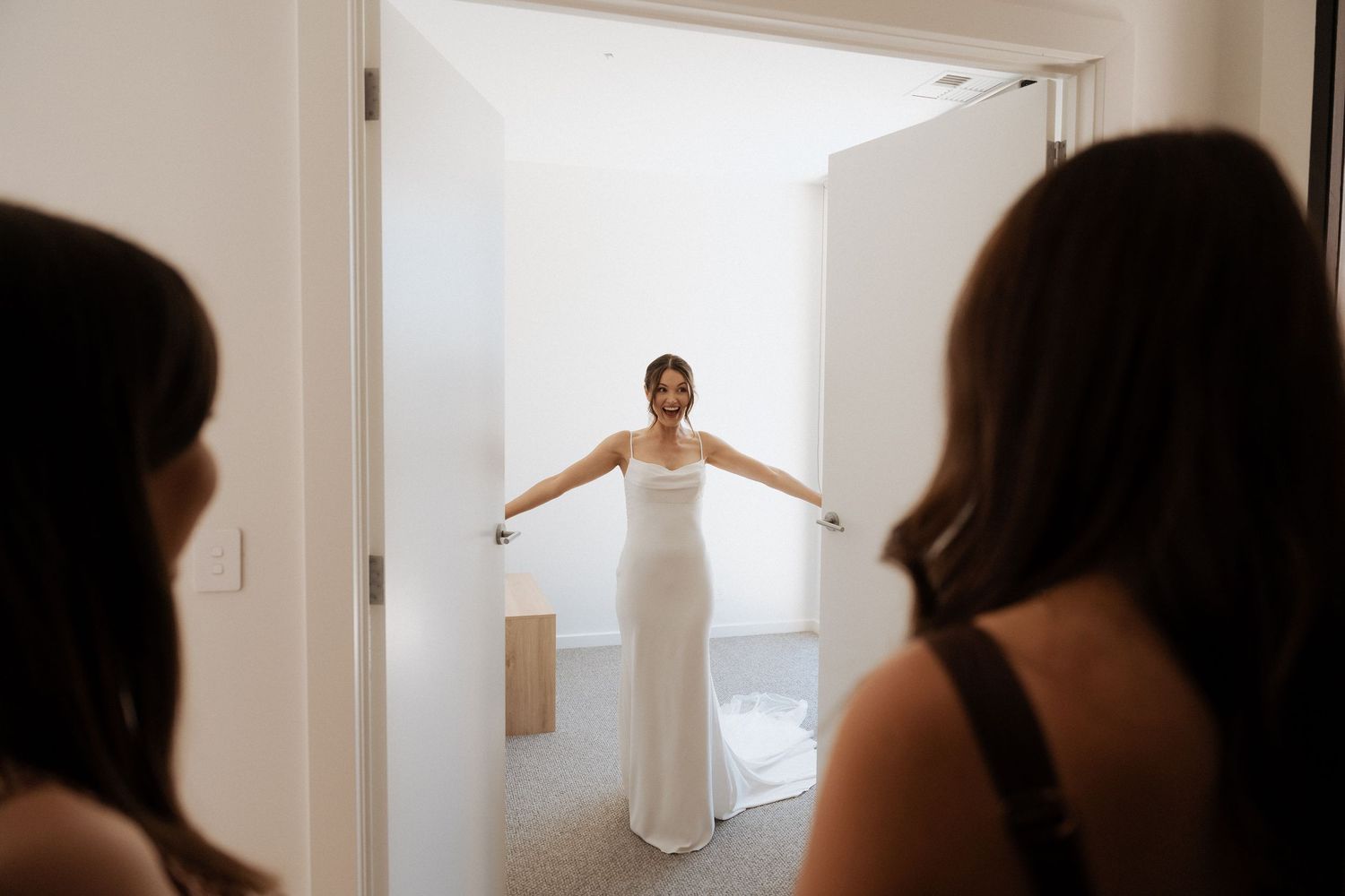 Silhouettes against bright window during wedding preparations.