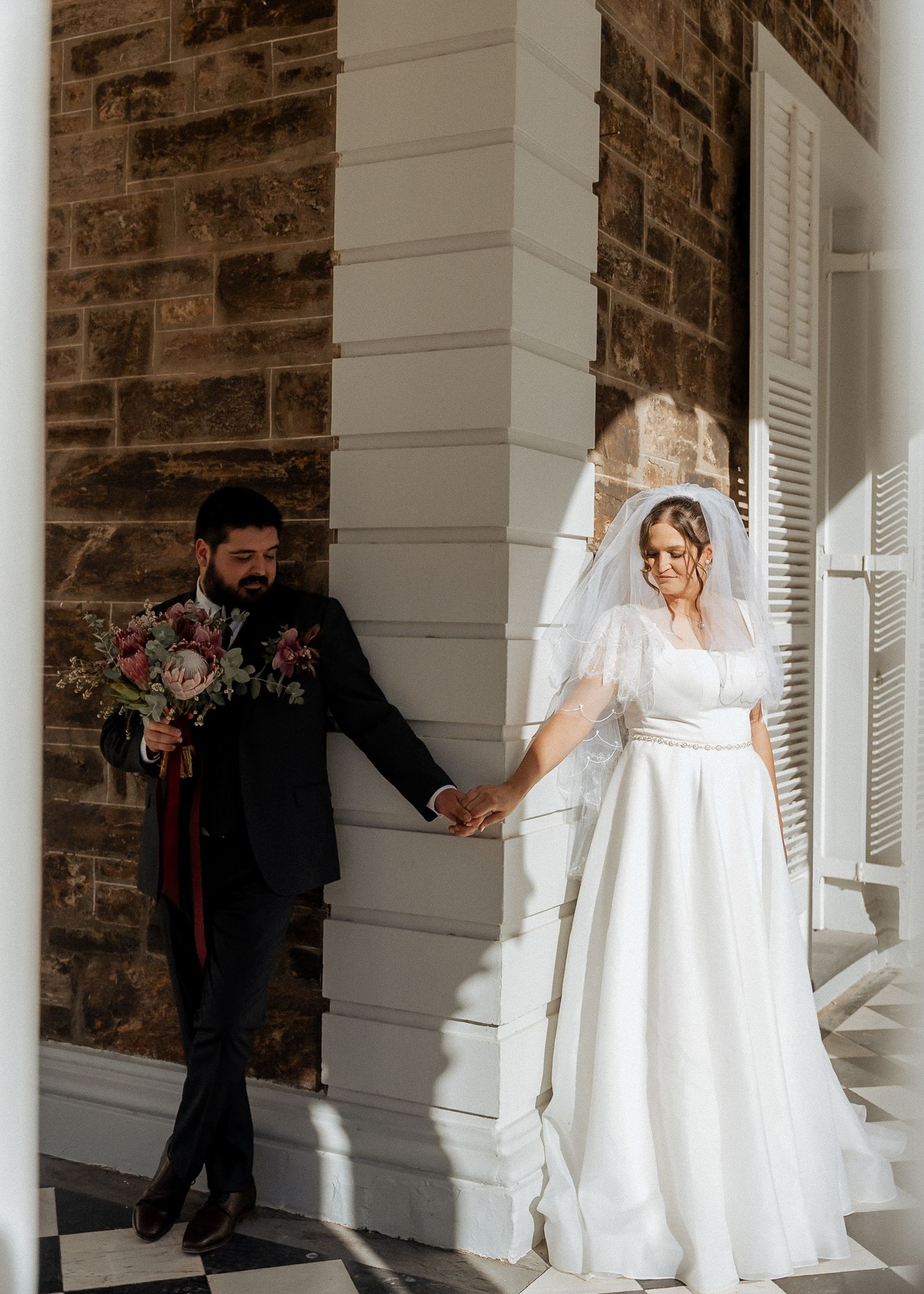 Wedding dress visible through white columns of a classic stone building.