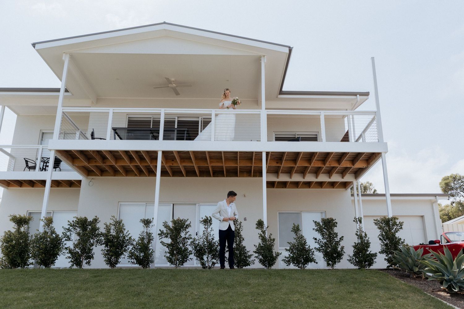 Modern white architectural building with clean lines and balconies against clear sky.