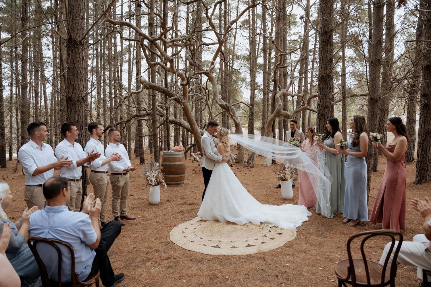 Wedding celebration in pine forest with rustic wooden chairs and natural decor. captured by braytmedia