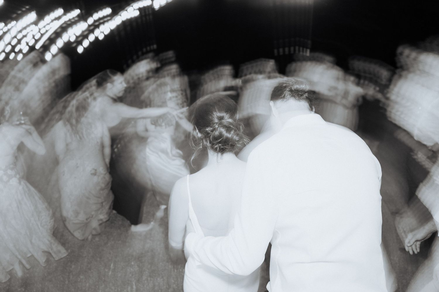 An artistic long exposure shot creates a dreamy effect of dancing figures in white at a reception.