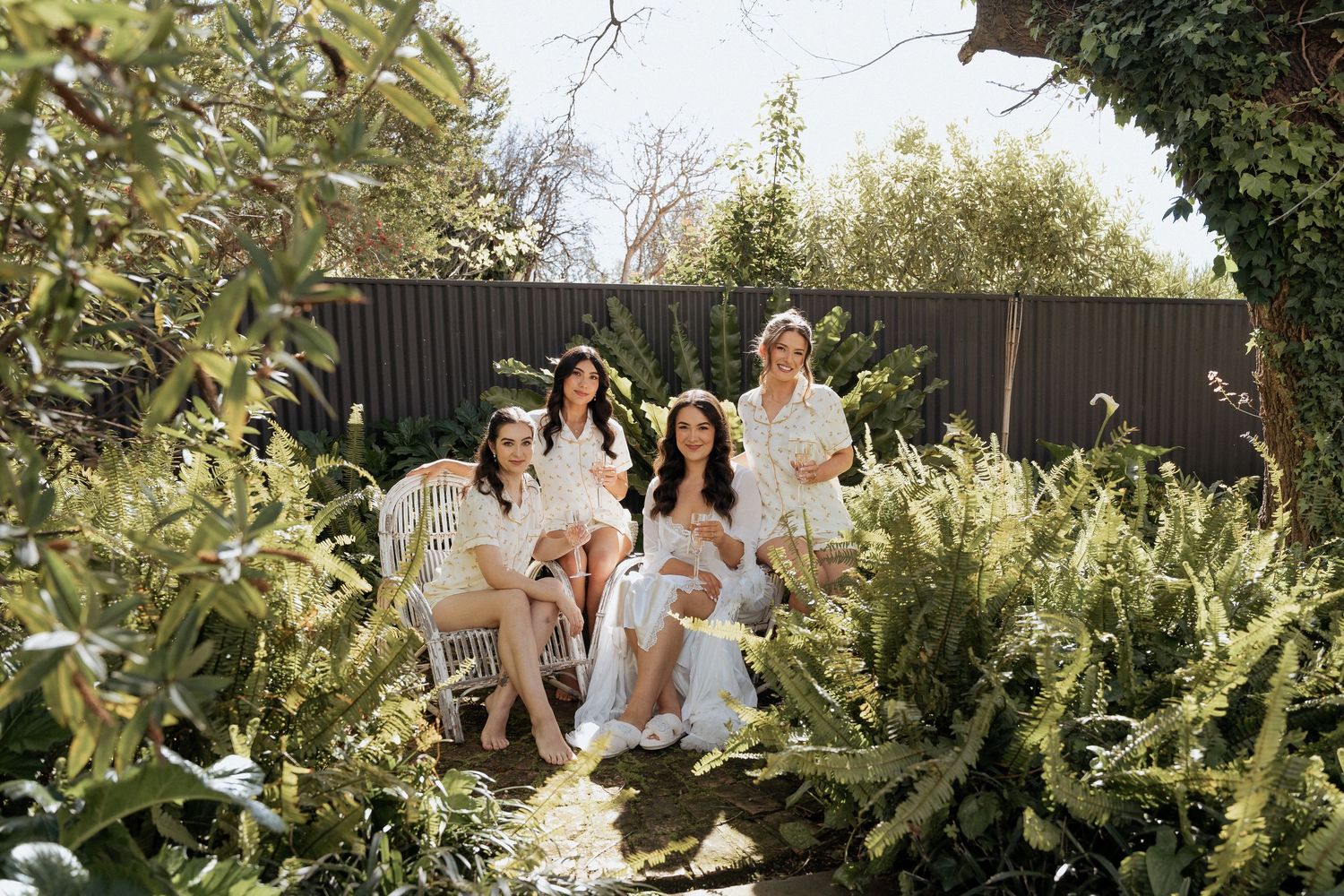 A group of people sitting together outdoors in a lush garden setting during a sunny day.
