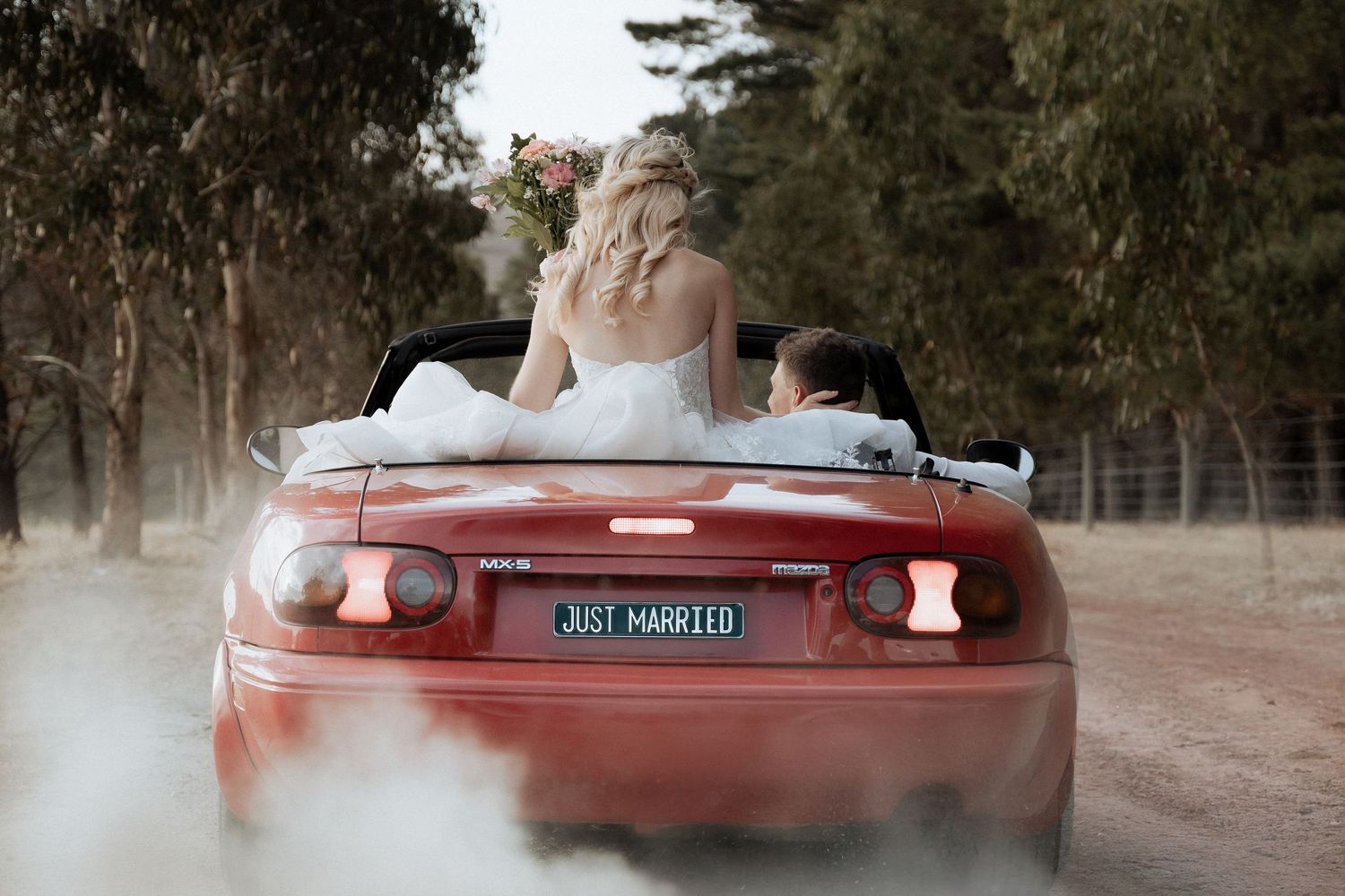 Vintage red convertible car photographed in a dreamy outdoor setting.