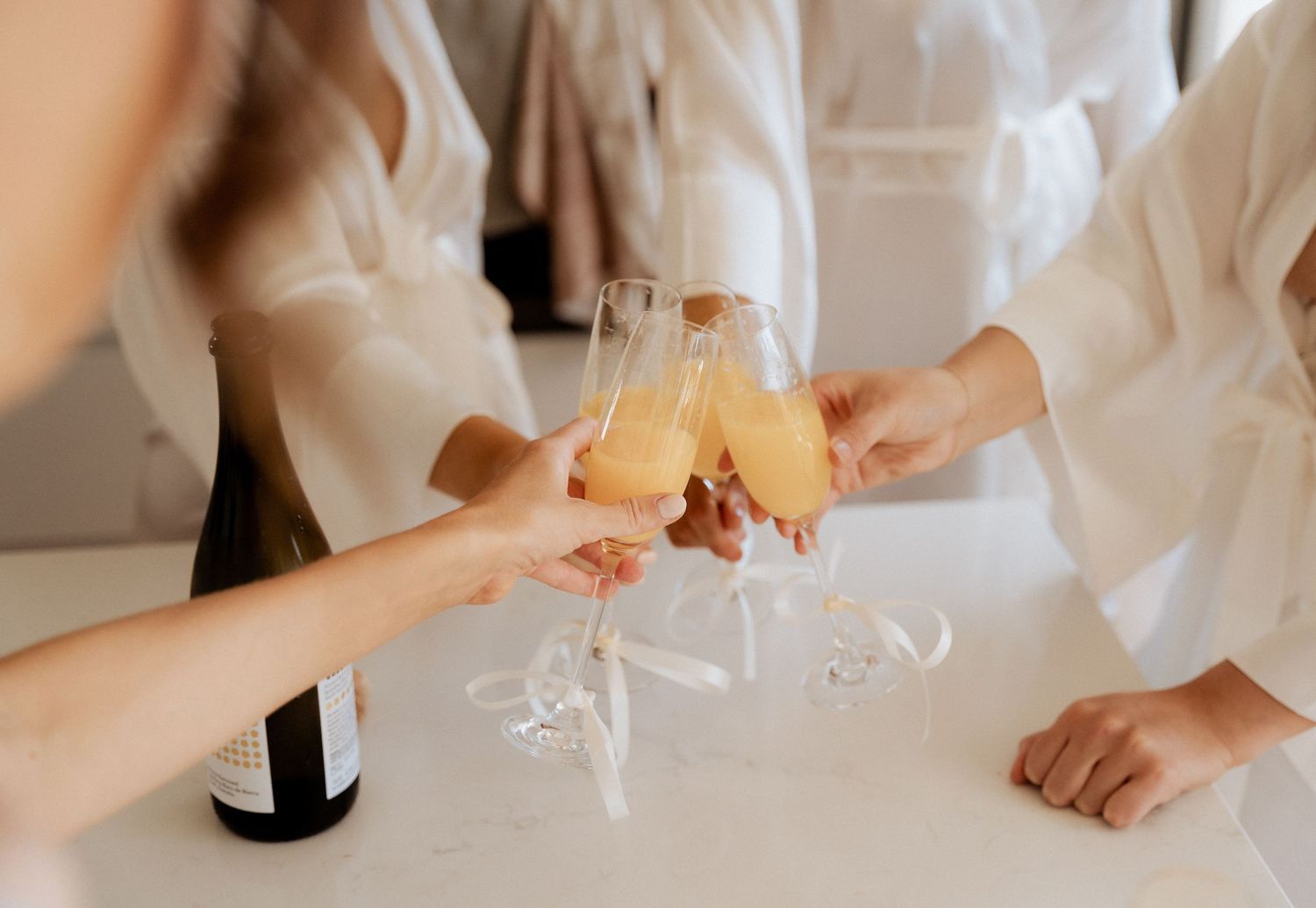 Hands holding champagne glasses during wedding celebration.