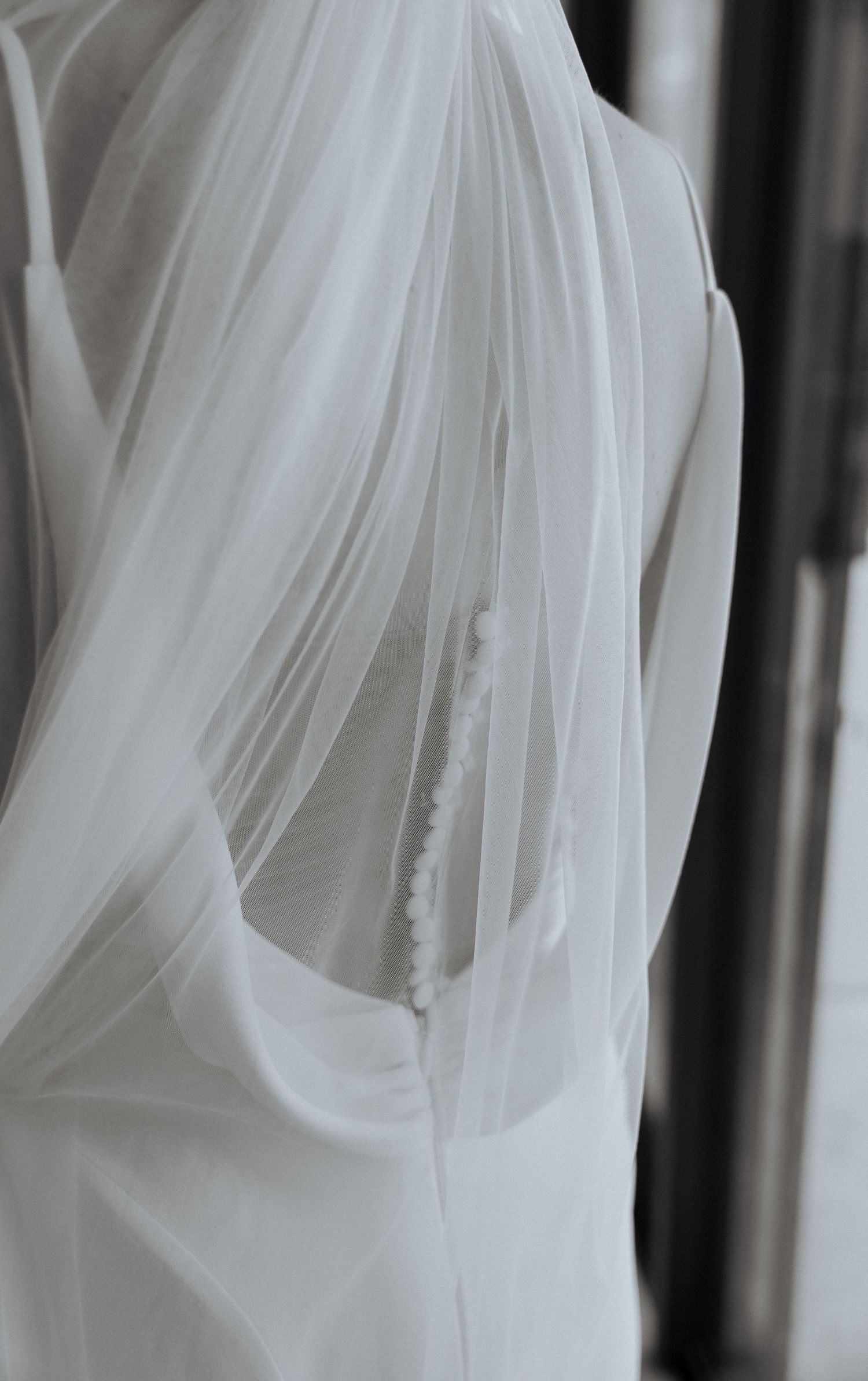 Close-up details of flowing white wedding dress fabric with delicate pleats and folds.
