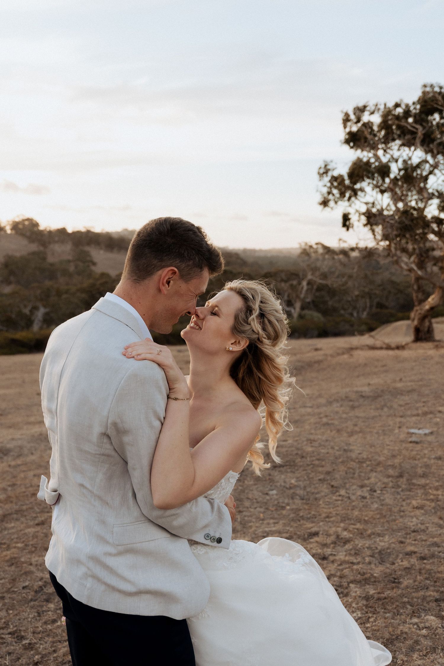 Romantic sunset photos of a couple dancing and embracing in an outdoor desert setting.