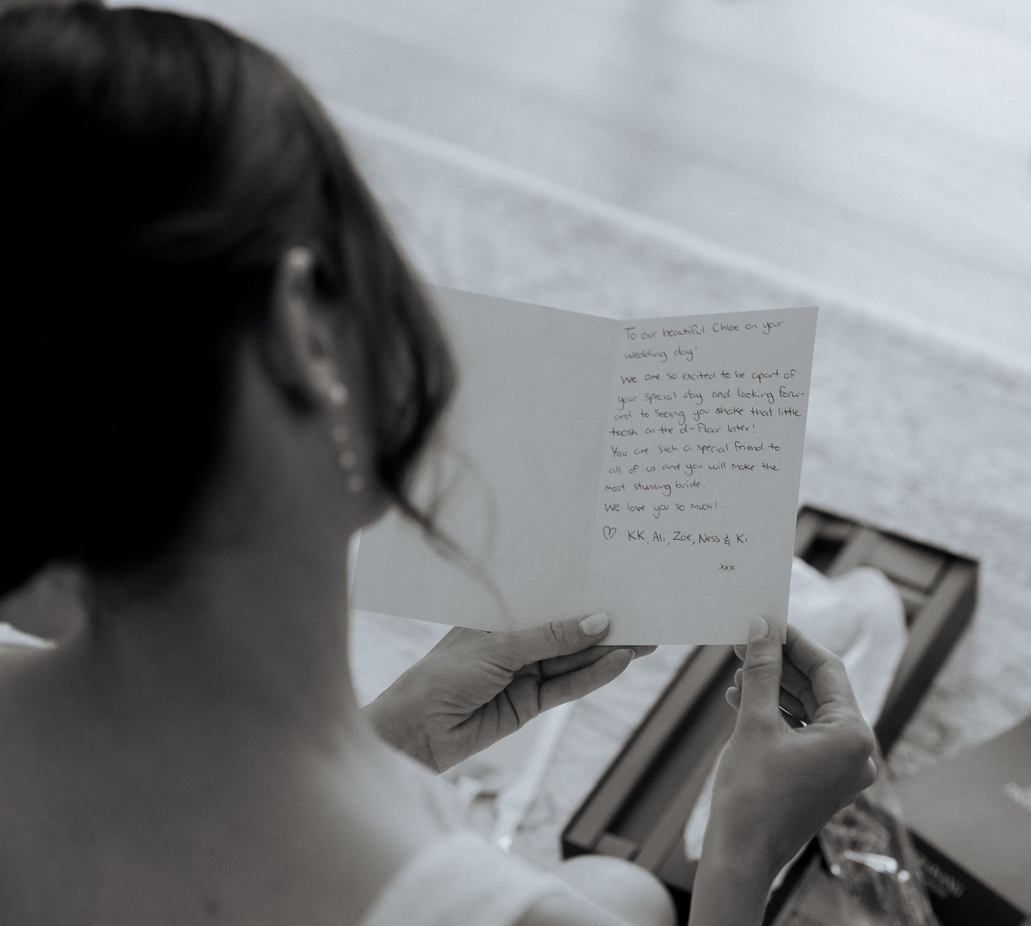 A black and white image showing someone reading a handwritten letter while getting ready.