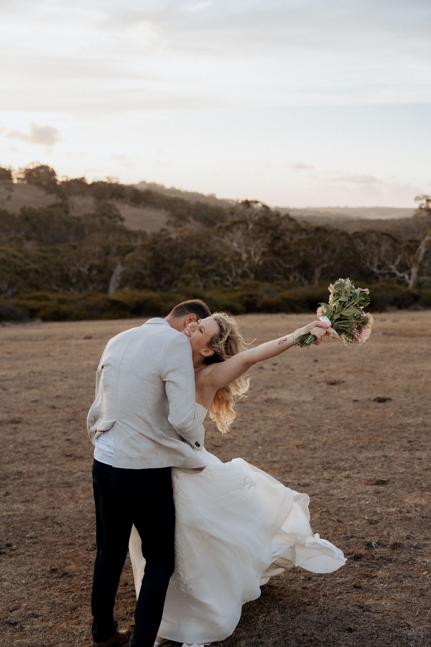 A romantic sunset wedding photo of newlyweds dancing in a rustic outdoor field. braytmedia weddings adelaide