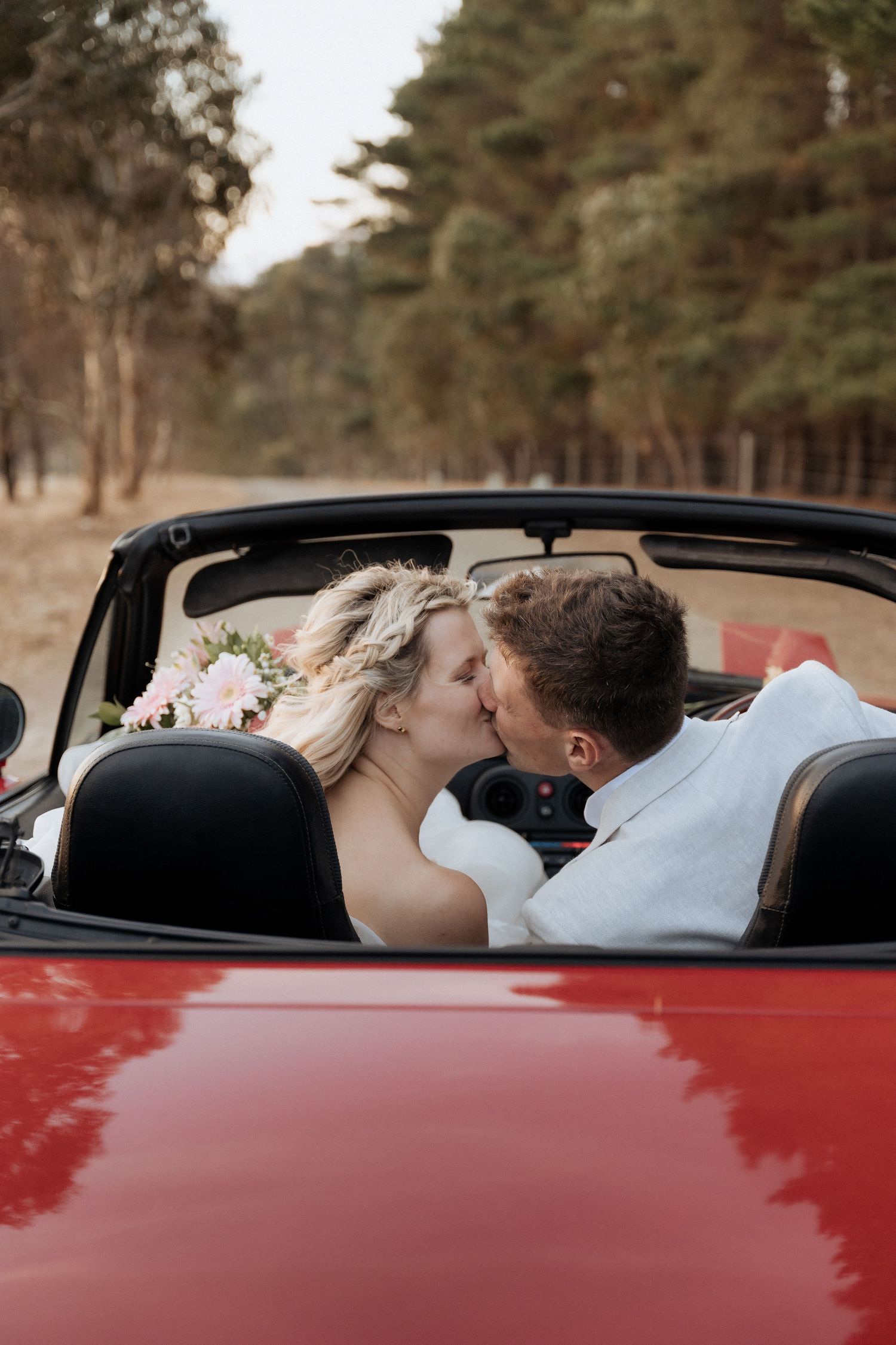 Intimate moment captured in vintage red convertible car on wedding day. captured by braytmedia