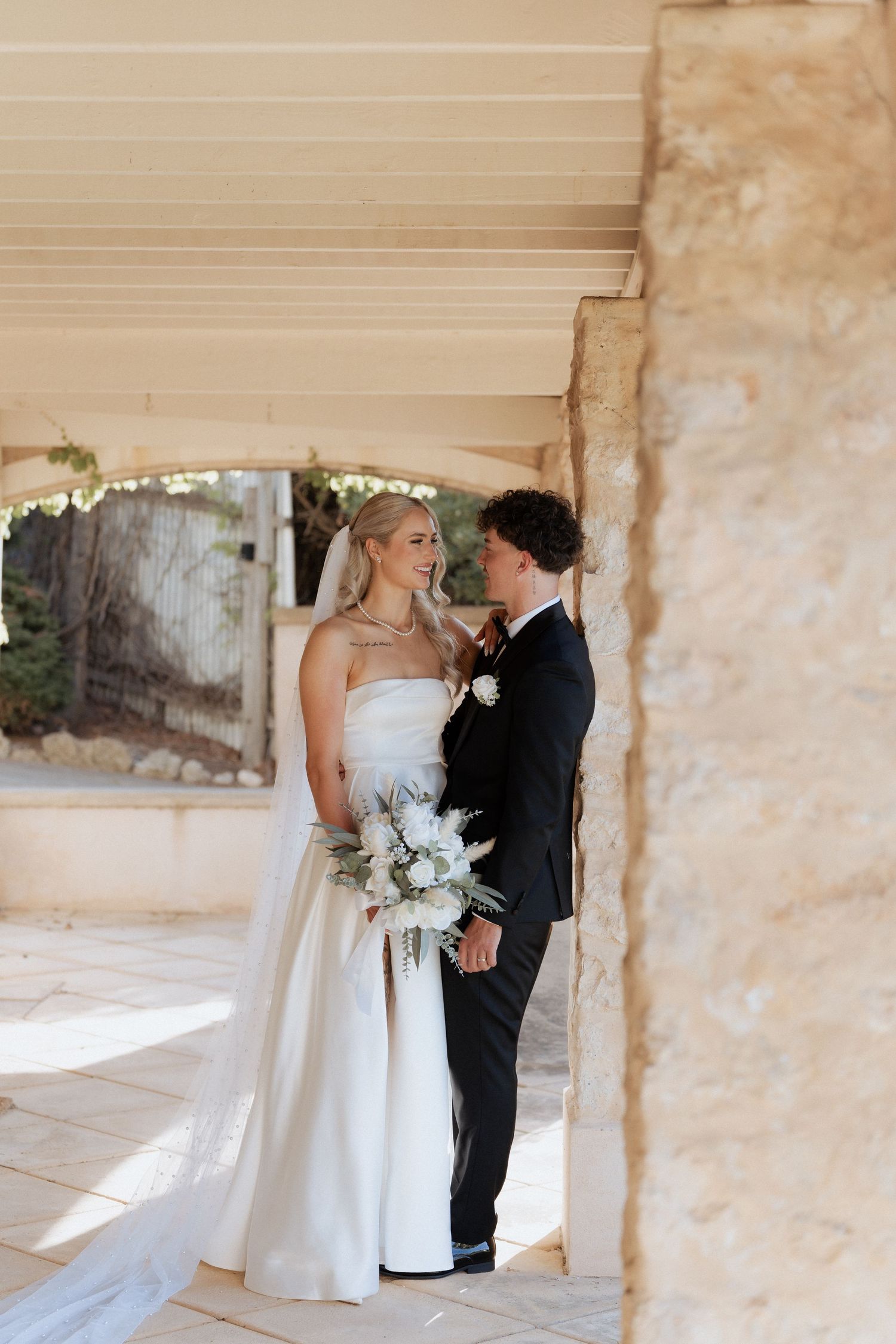 Couple shares intimate moments in a rustic stone archway setting. at the alton house in pt willunga, images by braytmedia
