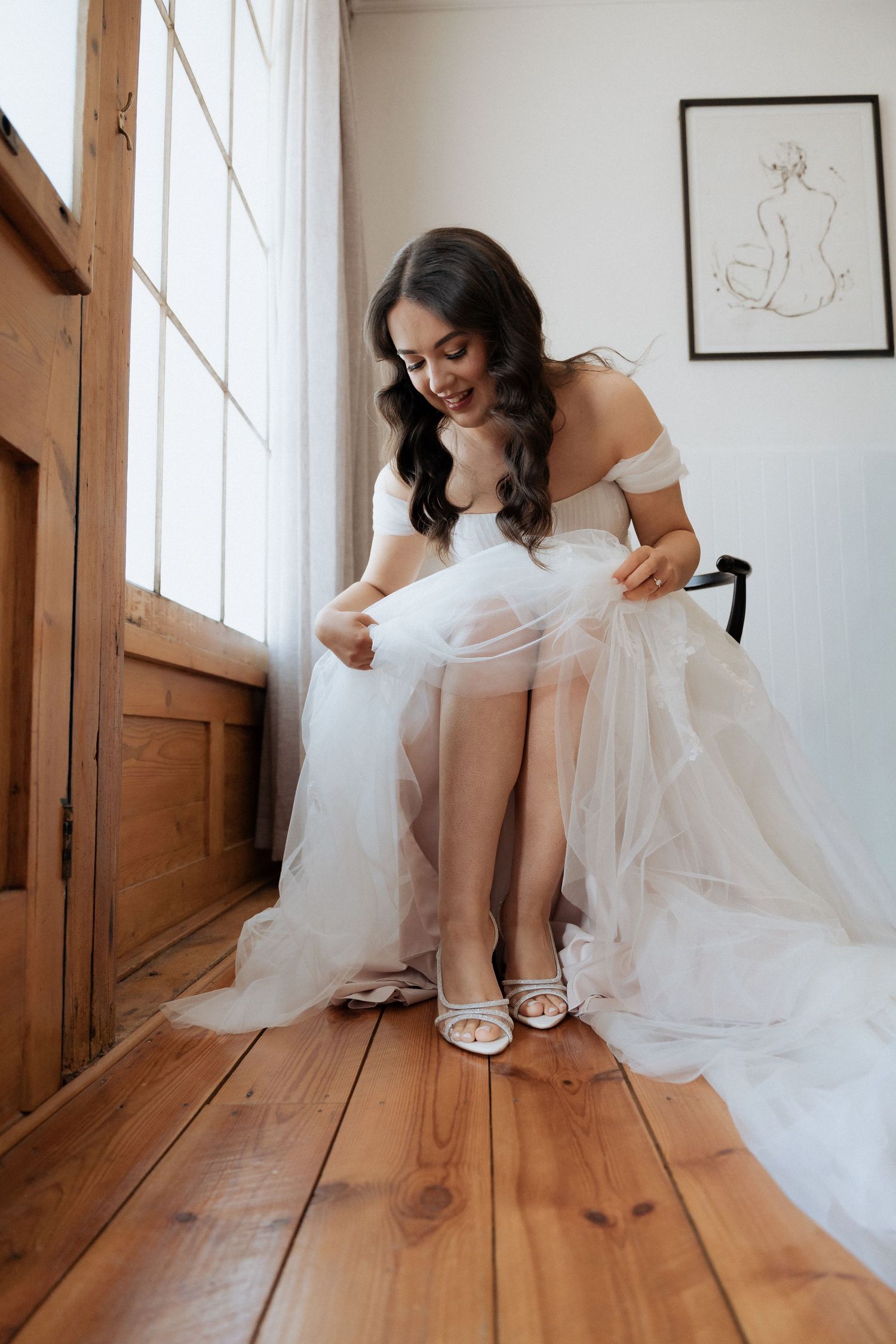 A bride in a white gown sits on a wooden floor adjusting her shoes in a series of candid moments.