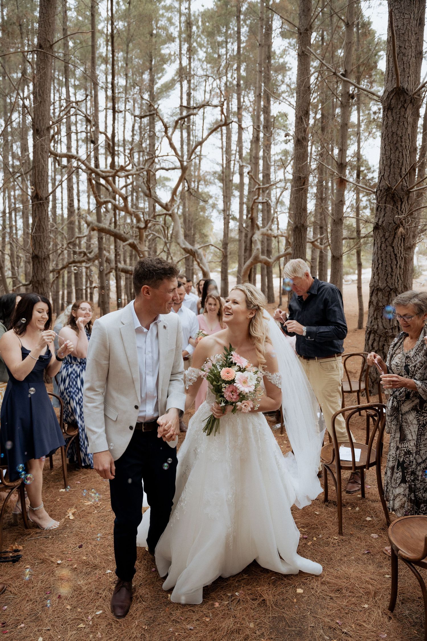 Wedding party gathered among tall pine trees for outdoor forest ceremony captured by braytmedia