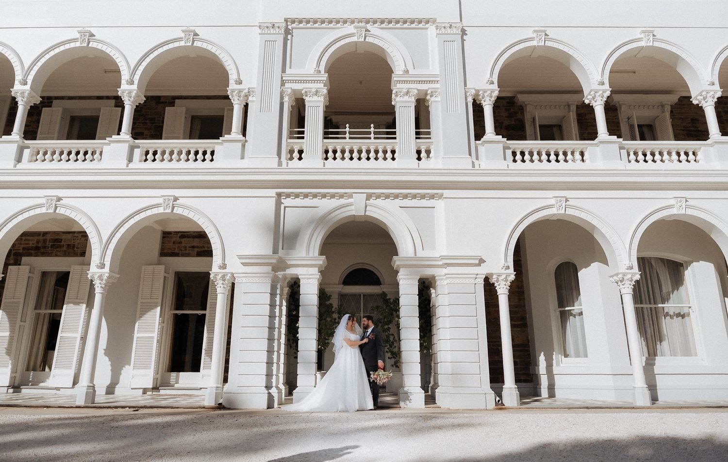 Elegant white colonial architecture with repeating arches and balustrades.