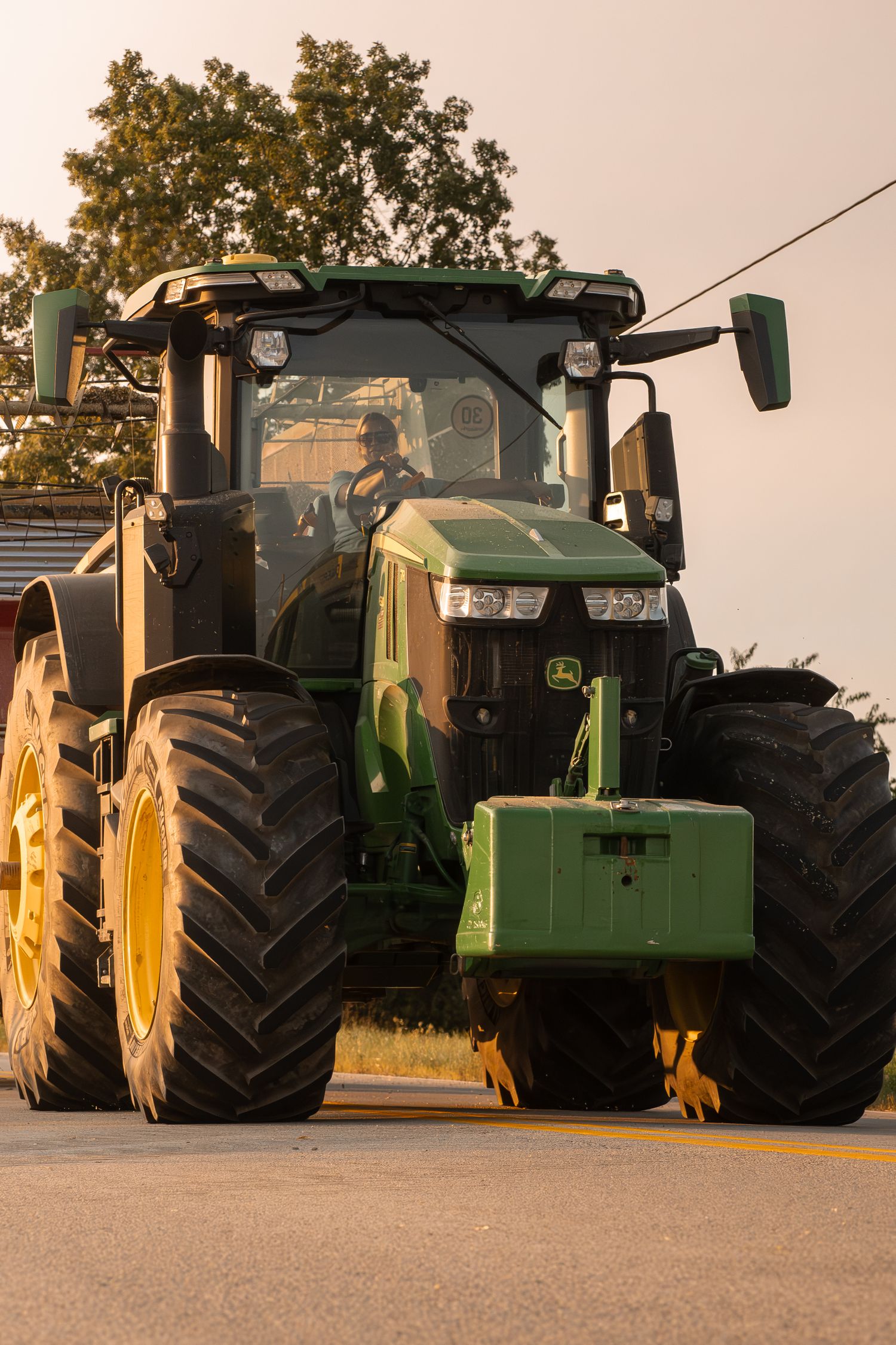 Row of parked John Deere tractors with large wheels lined up at golden hour.