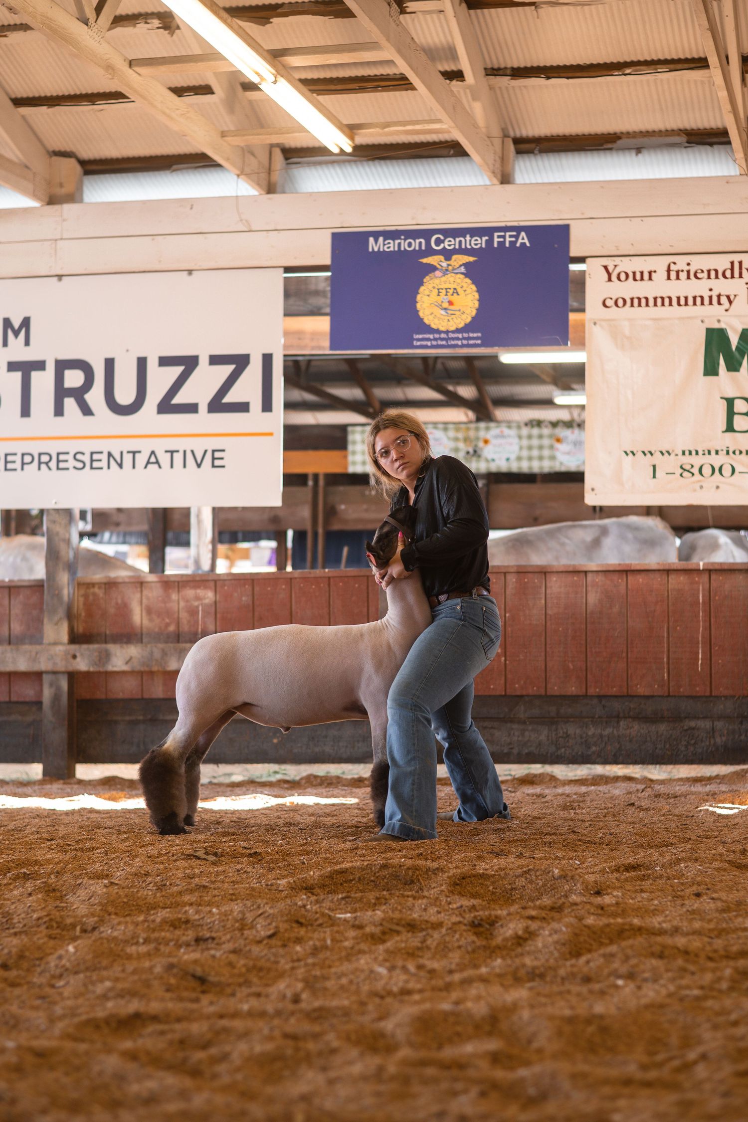 Person practicing horseback riding techniques in an indoor arena with FFA banners and sponsorship signage.