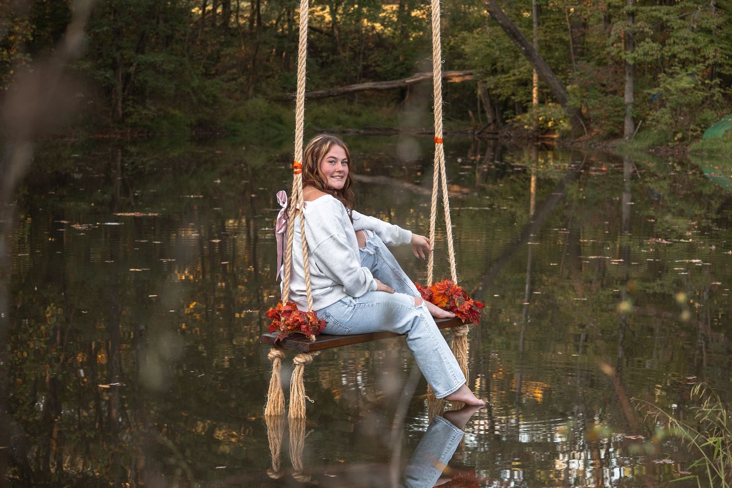 A person in light blue clothing swings over a tranquil pond surrounded by trees in a series of action shots.