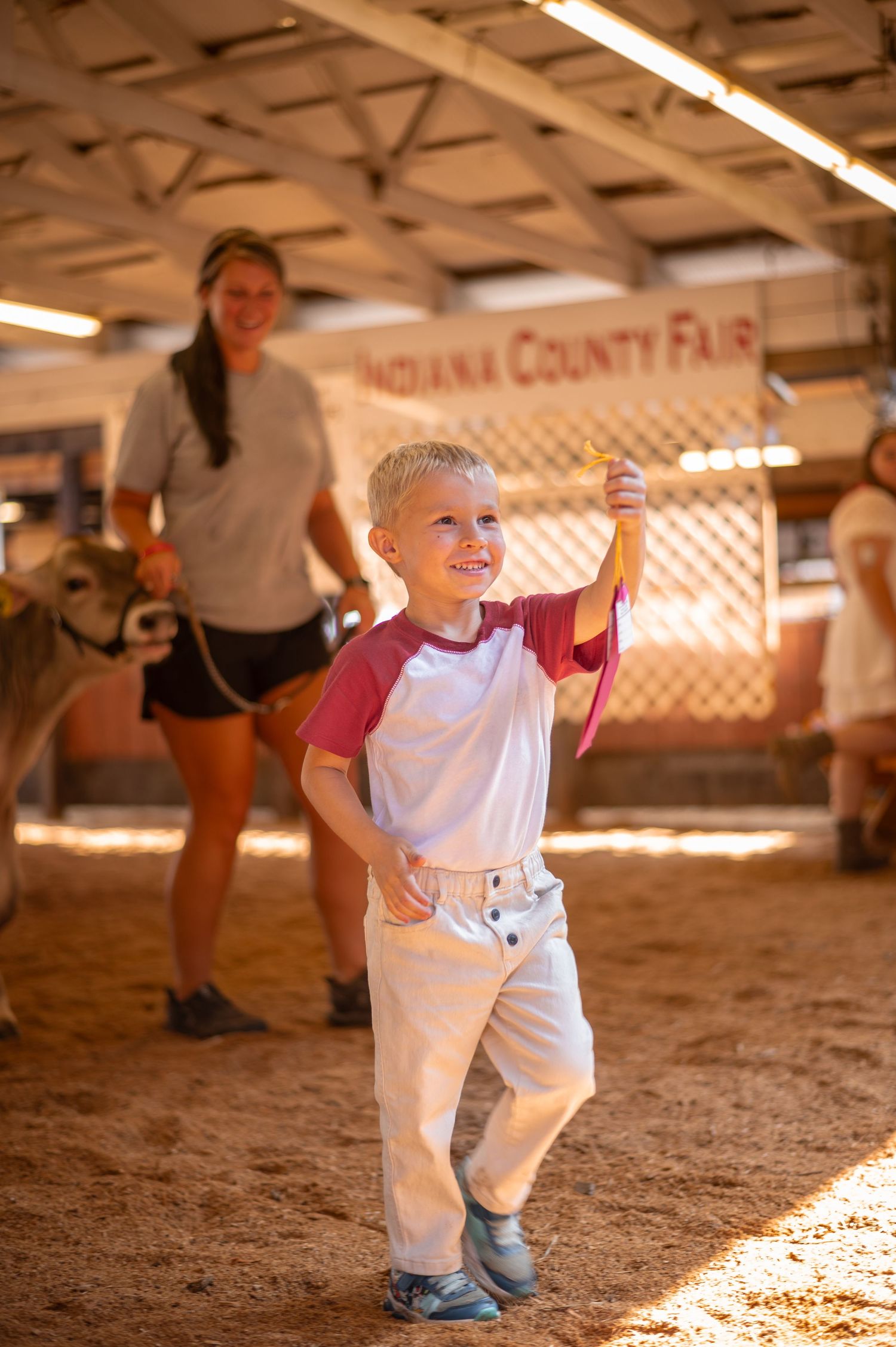 A scene from a county fair with wood shavings on the ground under indoor lighting.