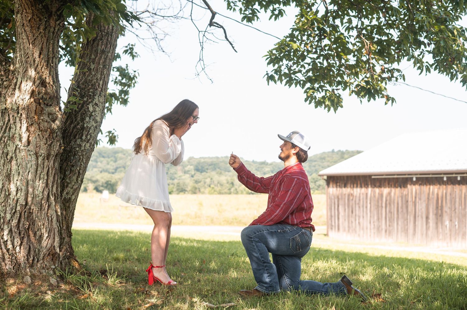 Playful engagement photography session in a scenic outdoor setting with trees.