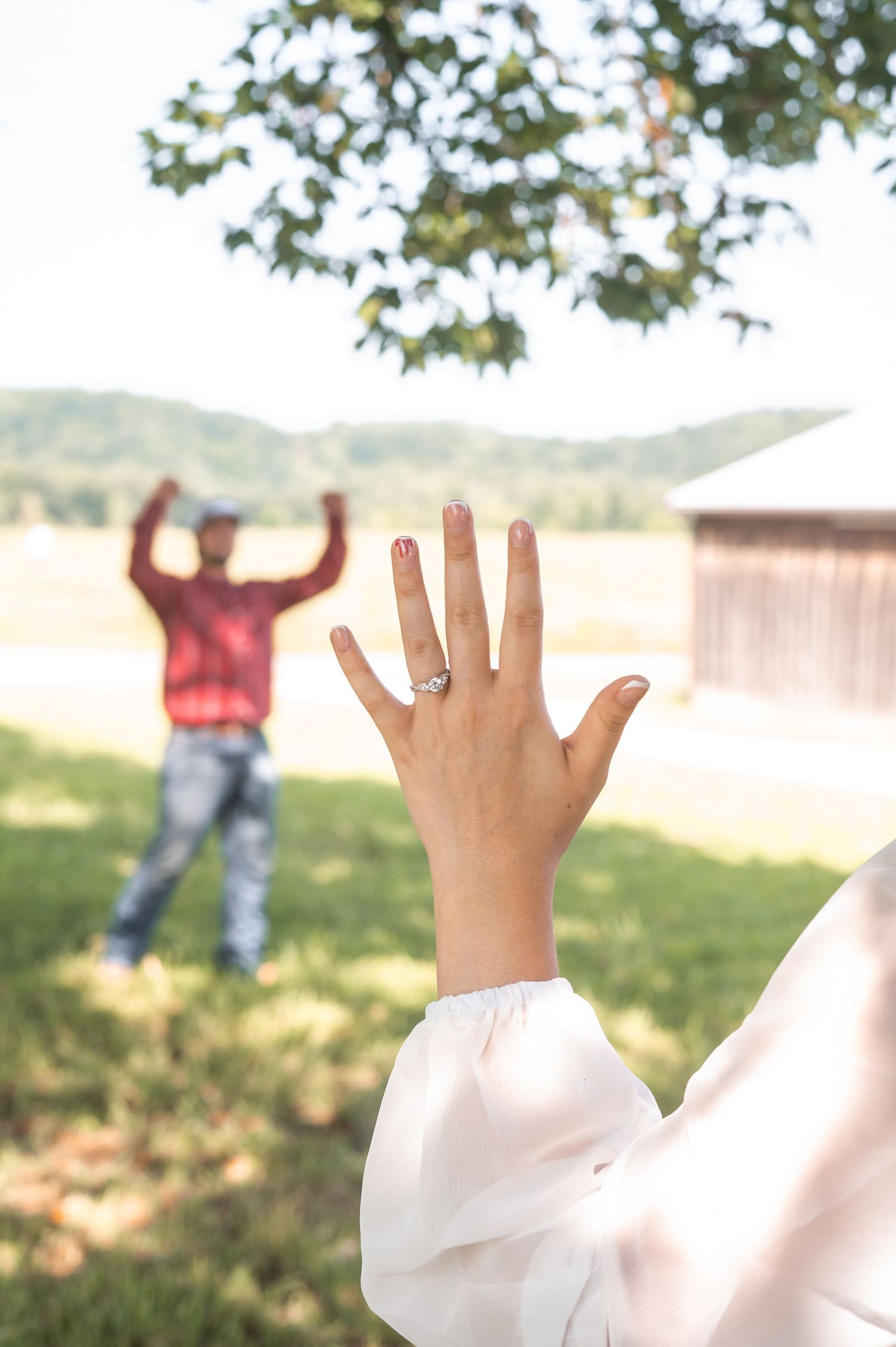 Close-up of an engagement ring being showcased against a sunlit outdoor background.