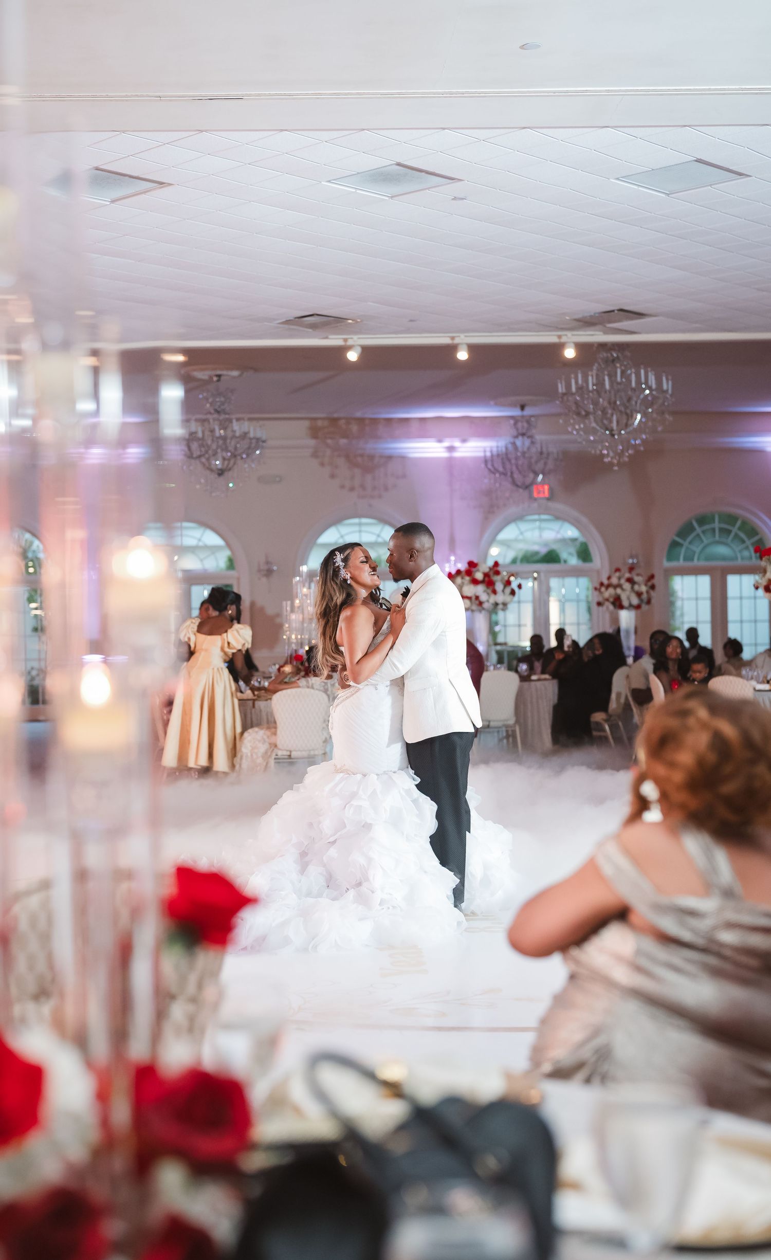 Wedding reception ballroom with couples dancing under crystal chandeliers.
