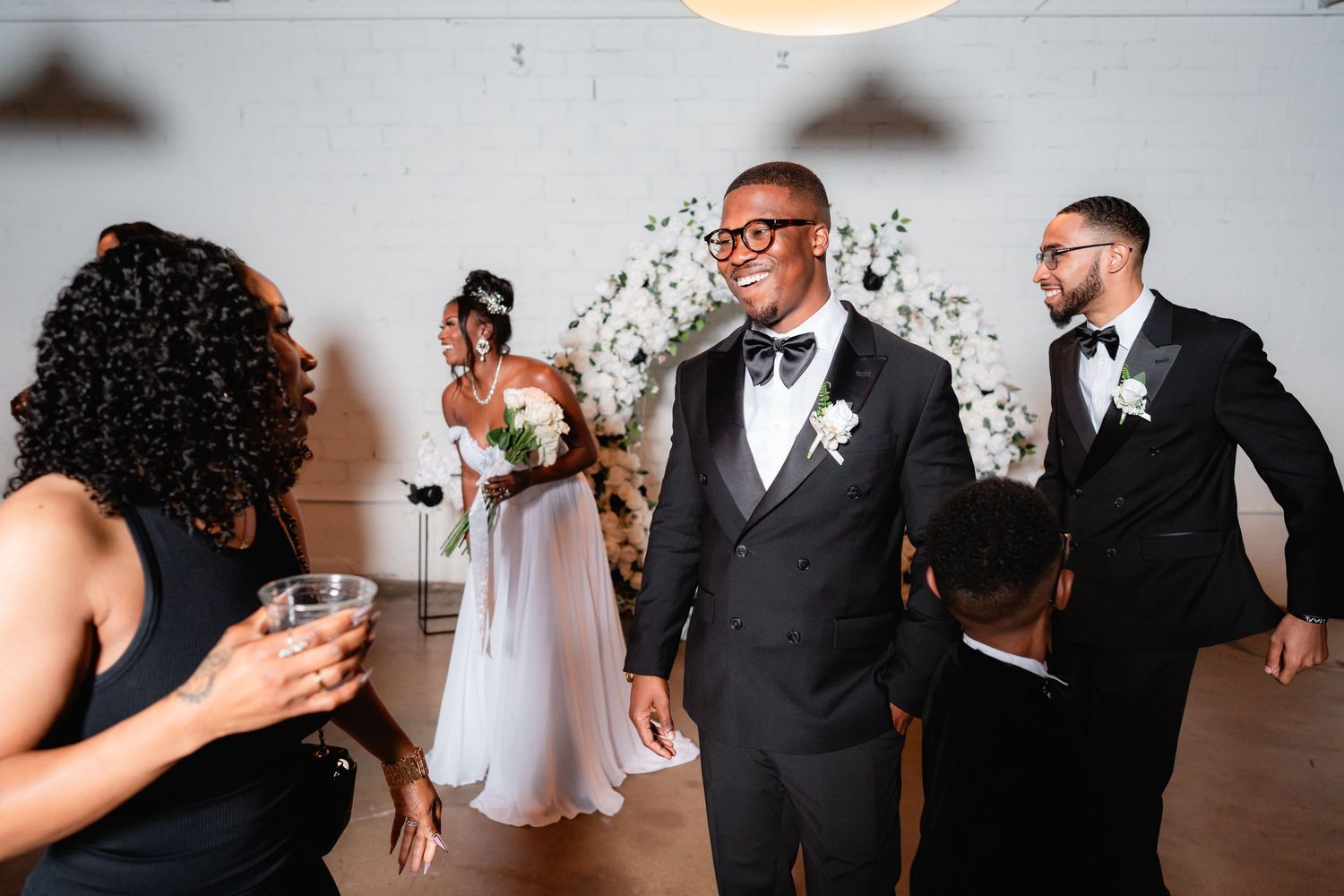 Joyful reception moment in modern venue with wedding party in formal attire.