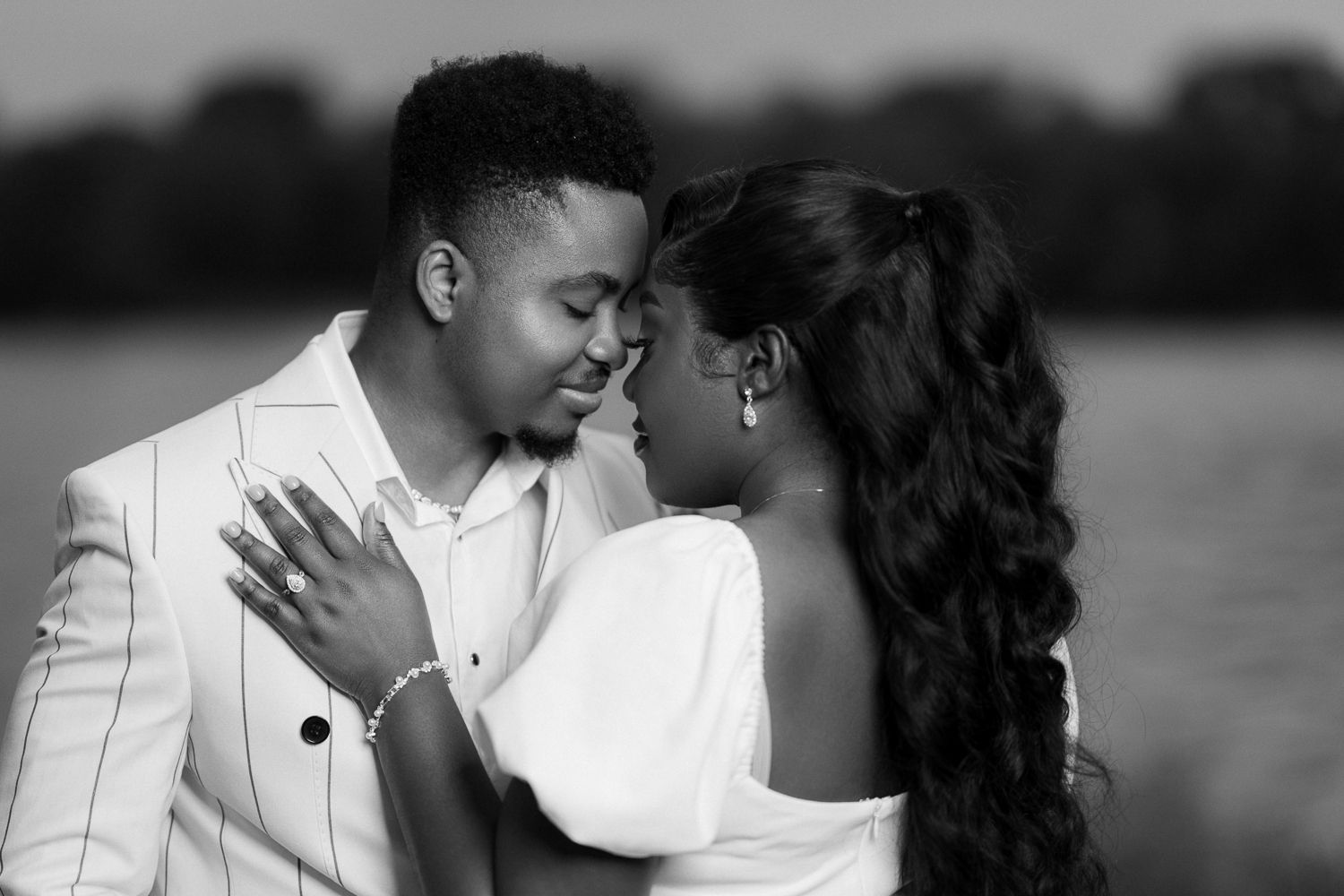 A romantic black and white photo series showing a couple in white outfits sharing intimate moments together outdoors.