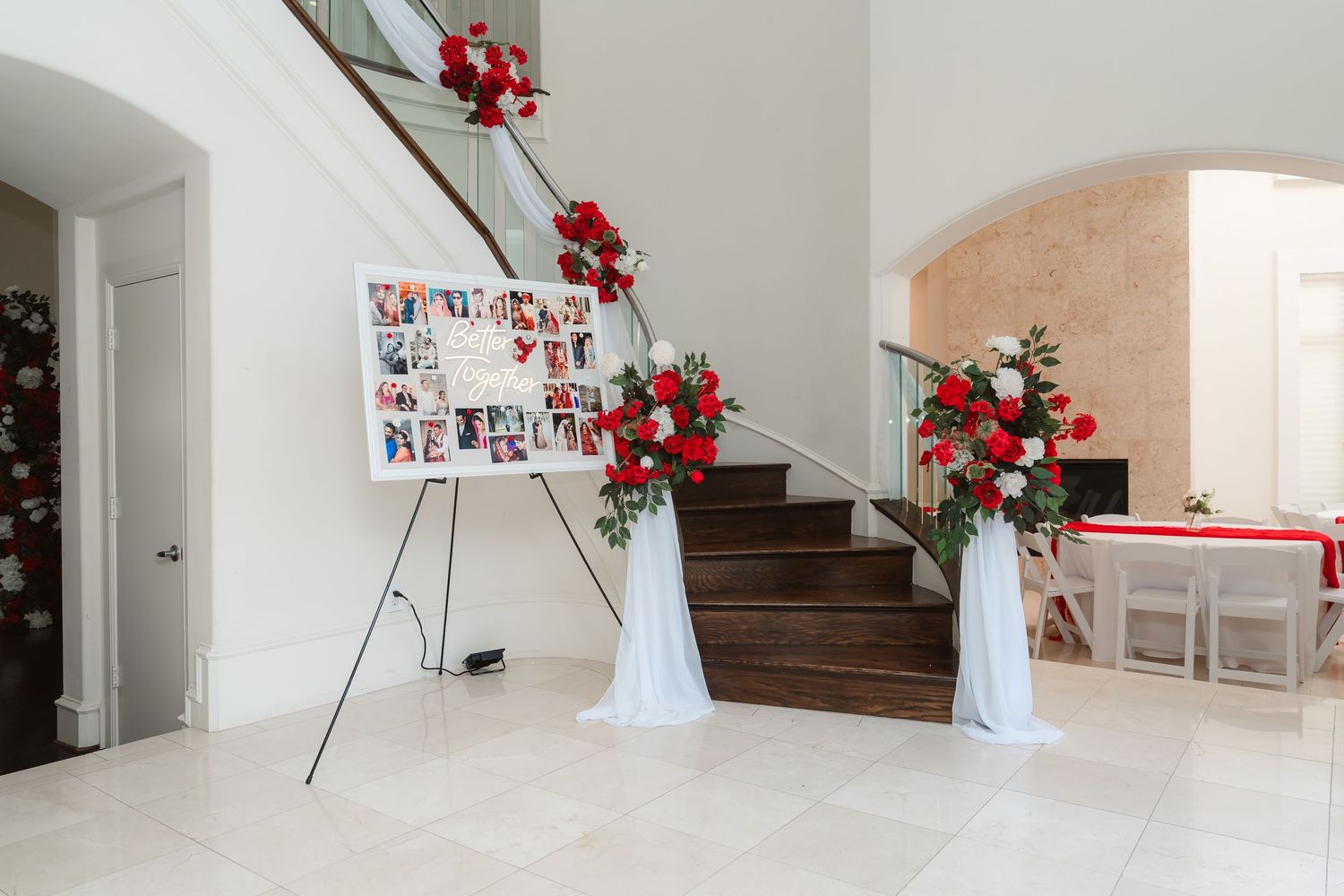Modern white interior staircase decorated with red floral arrangements in white vases against a white wall.