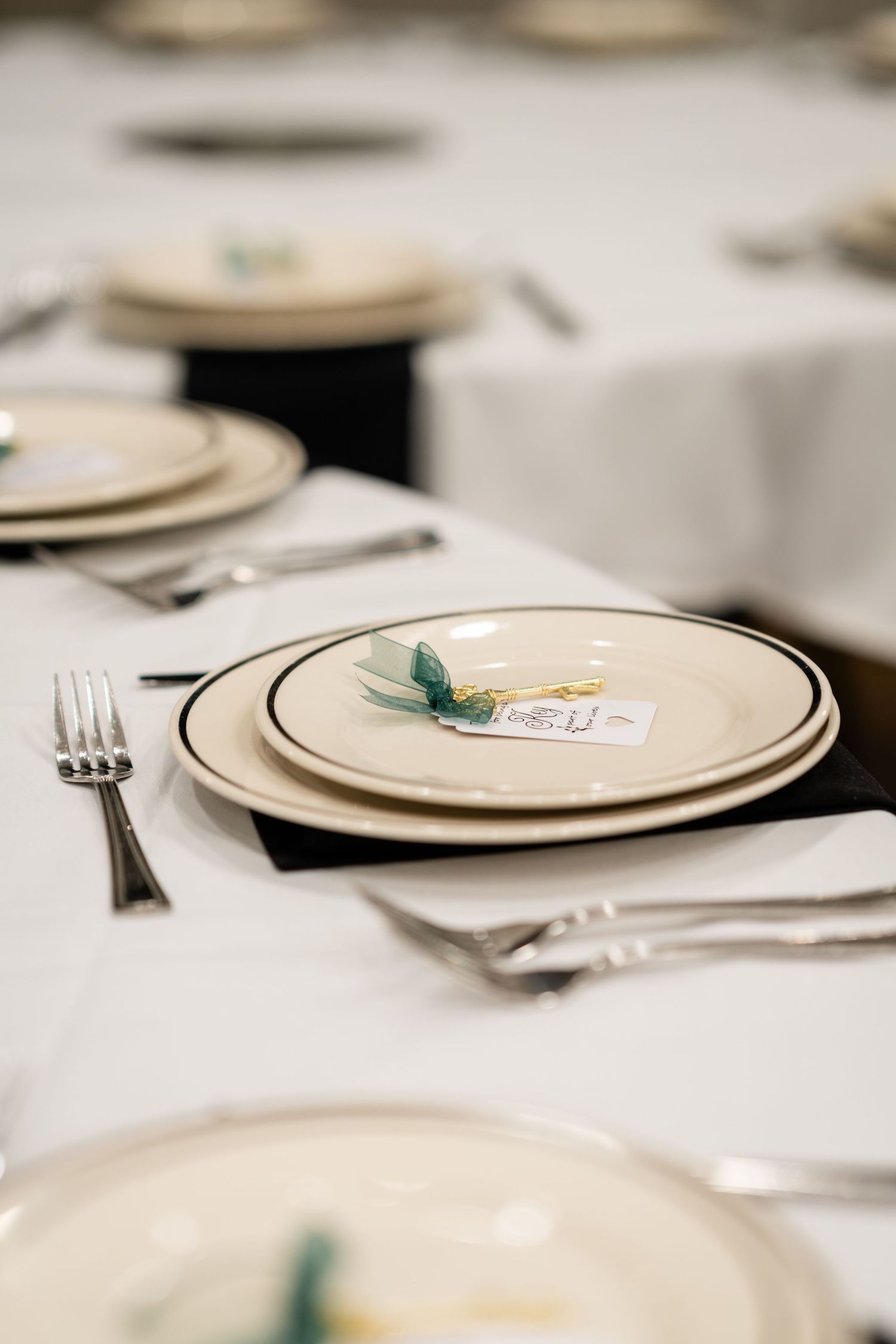 Elegant place settings with gold-rimmed plates and silverware on white tablecloth.