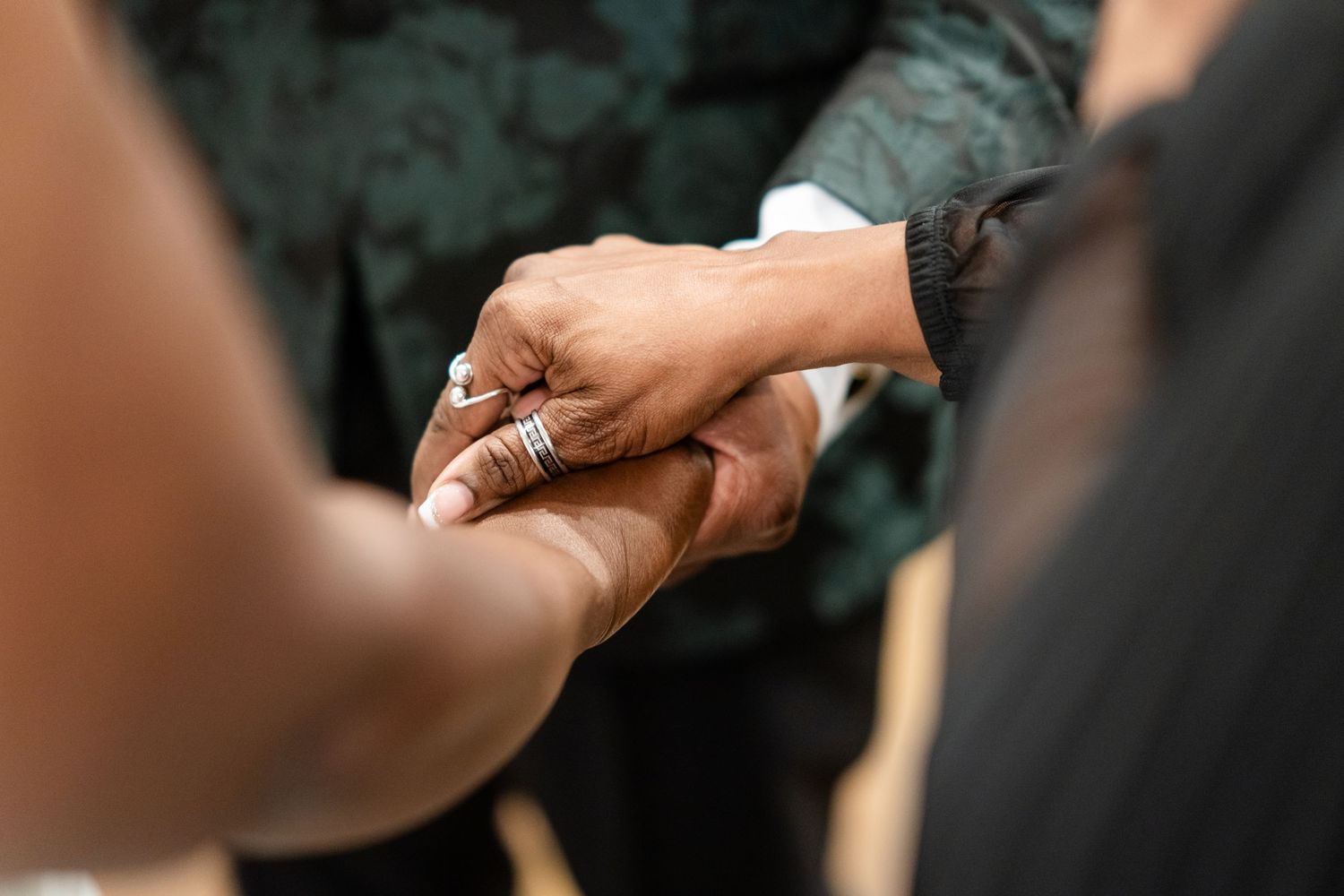 Close-up details of hands and rings during wedding ceremony.