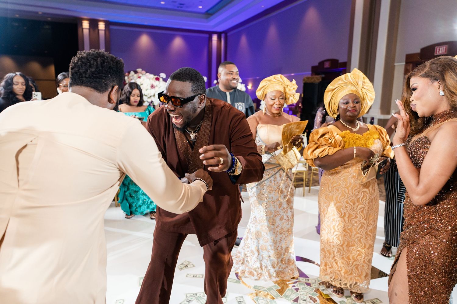 Wedding reception dance floor with guests celebrating under purple lighting.